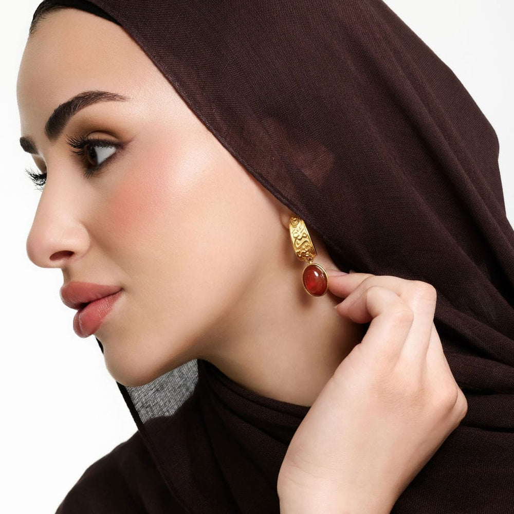 Photo of the model's left side profile showing the gold "With Hardship Comes Ease" Earring they are wearing on their left ear.