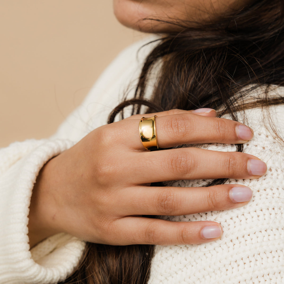 Woman wearing a gold Chunky Melt Ring on her middle finger, styled with a white knit sweater.