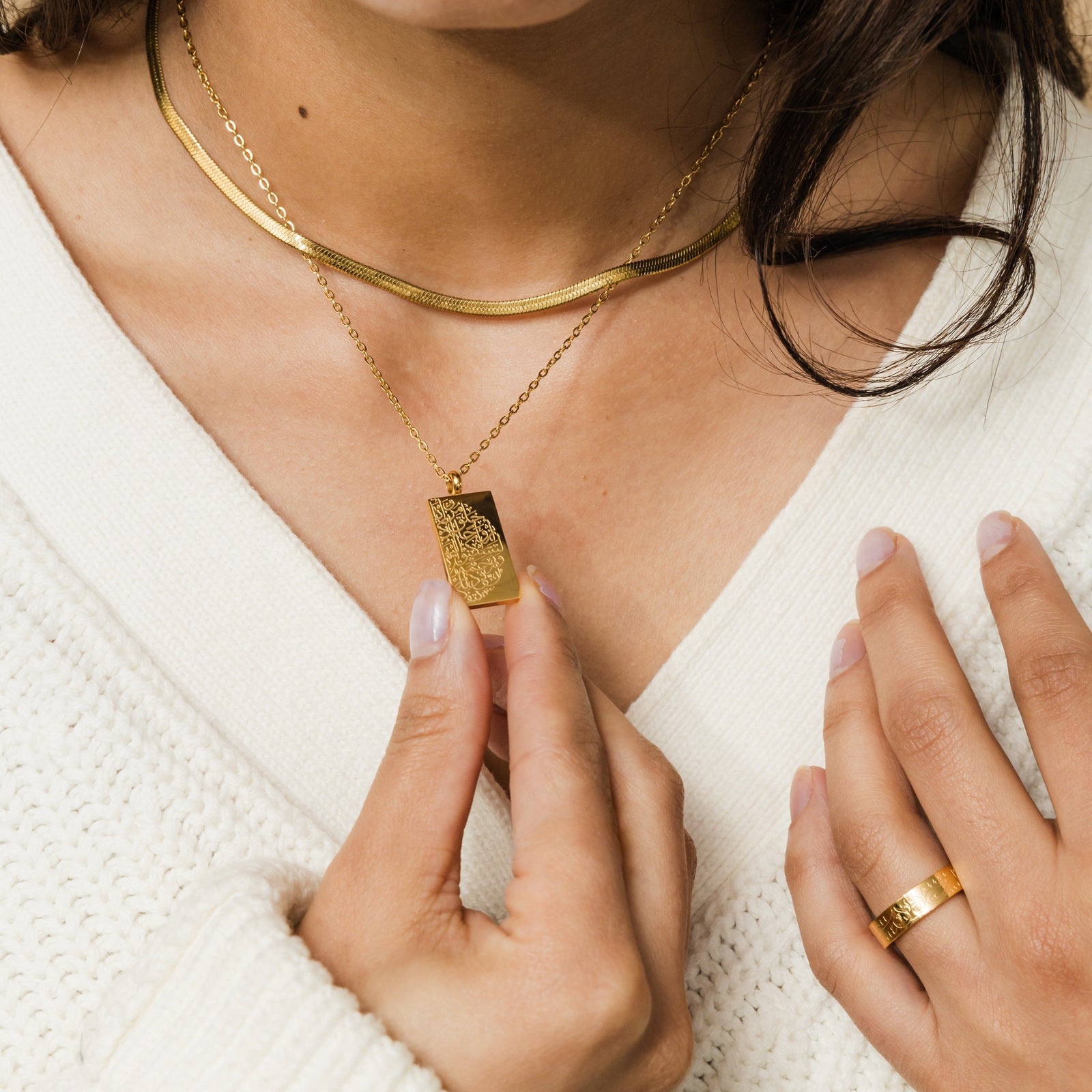 Close up of the gold "Tranquility in Them" Necklace as worn by the female model