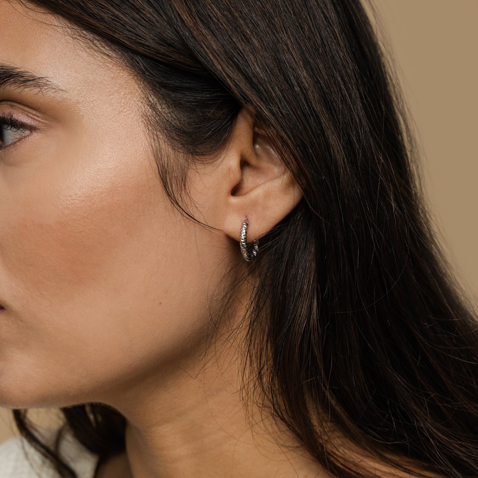 Close up of the silver Flake Hoops as worn by the model on their left ear.