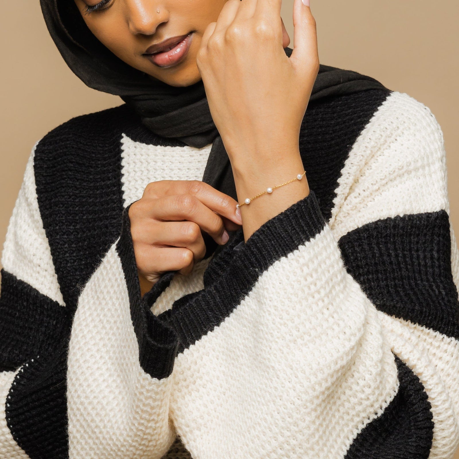 Photo of the model adjusting the Pearl Strand Bracelet on their wrist.