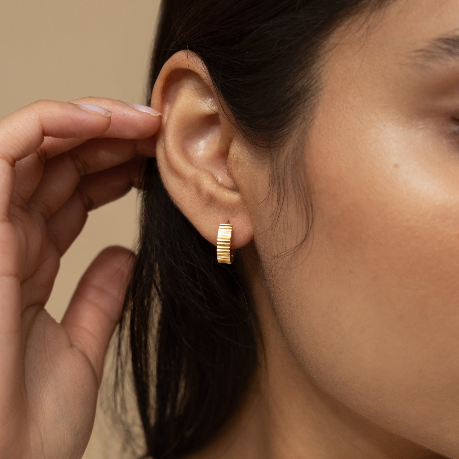 Close up of the gold Ridged Hoops as worn by the model on their right ear.