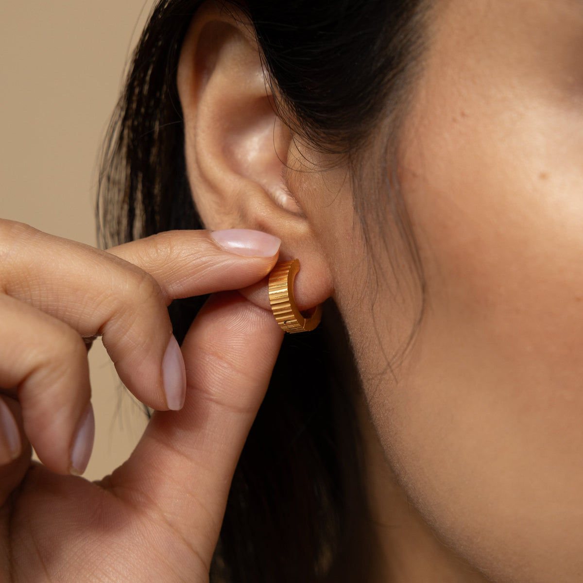 Close up of the gold Ridged Hoops as worn by the model on their right ear.