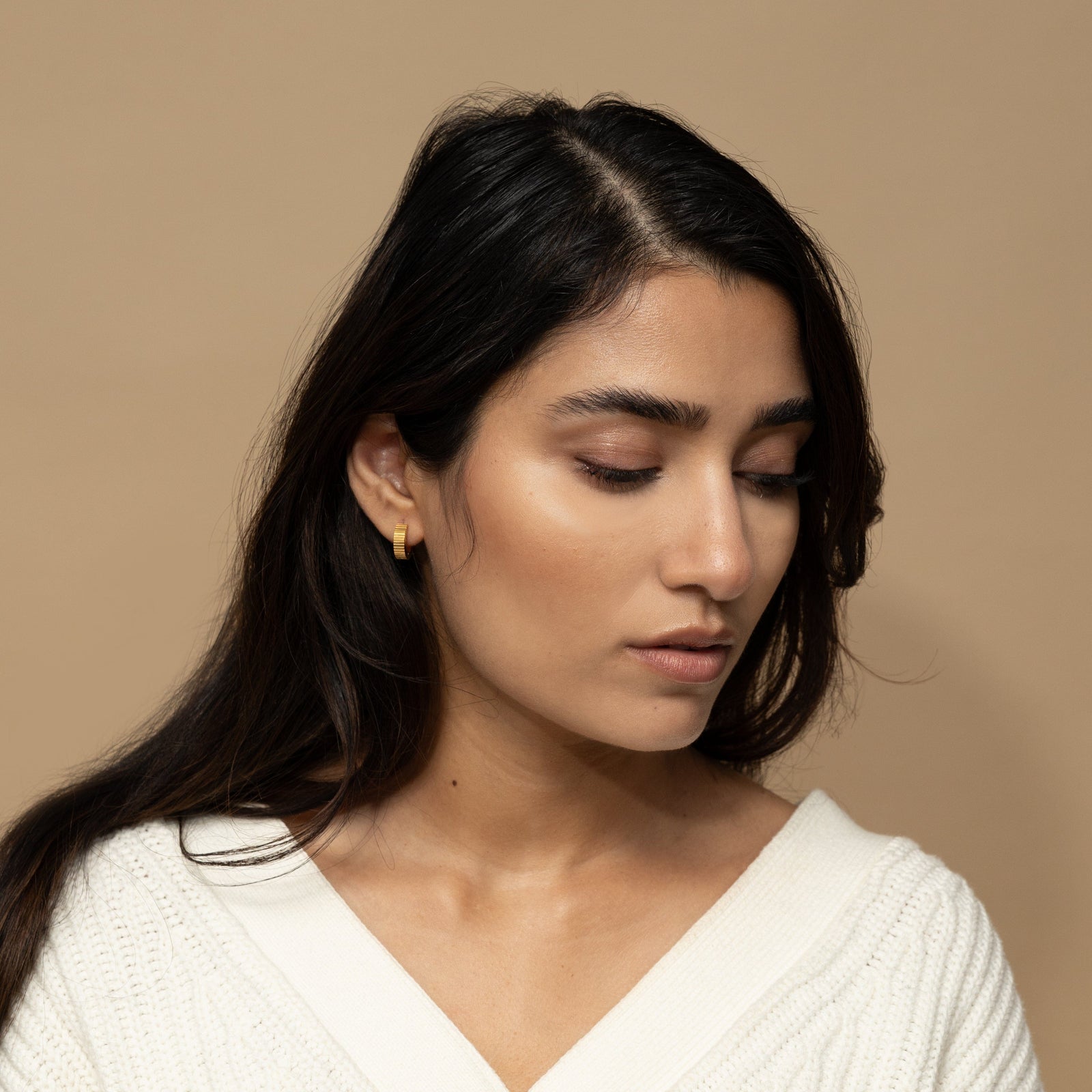 Photo of the model wearing the gold Ridged Hoops on their right ear.