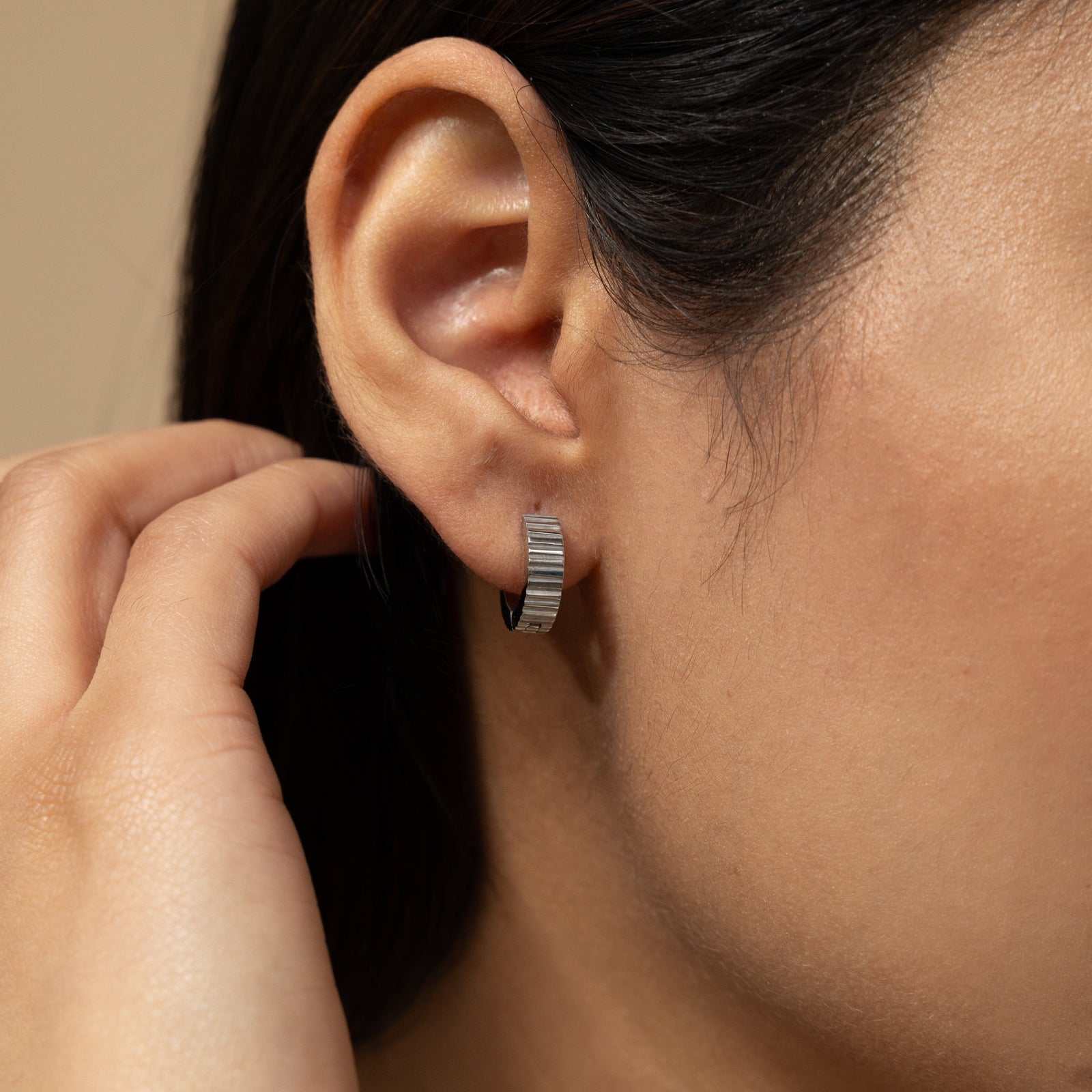 Close up of the silver Ridged Hoops as worn by the model on their right ear.