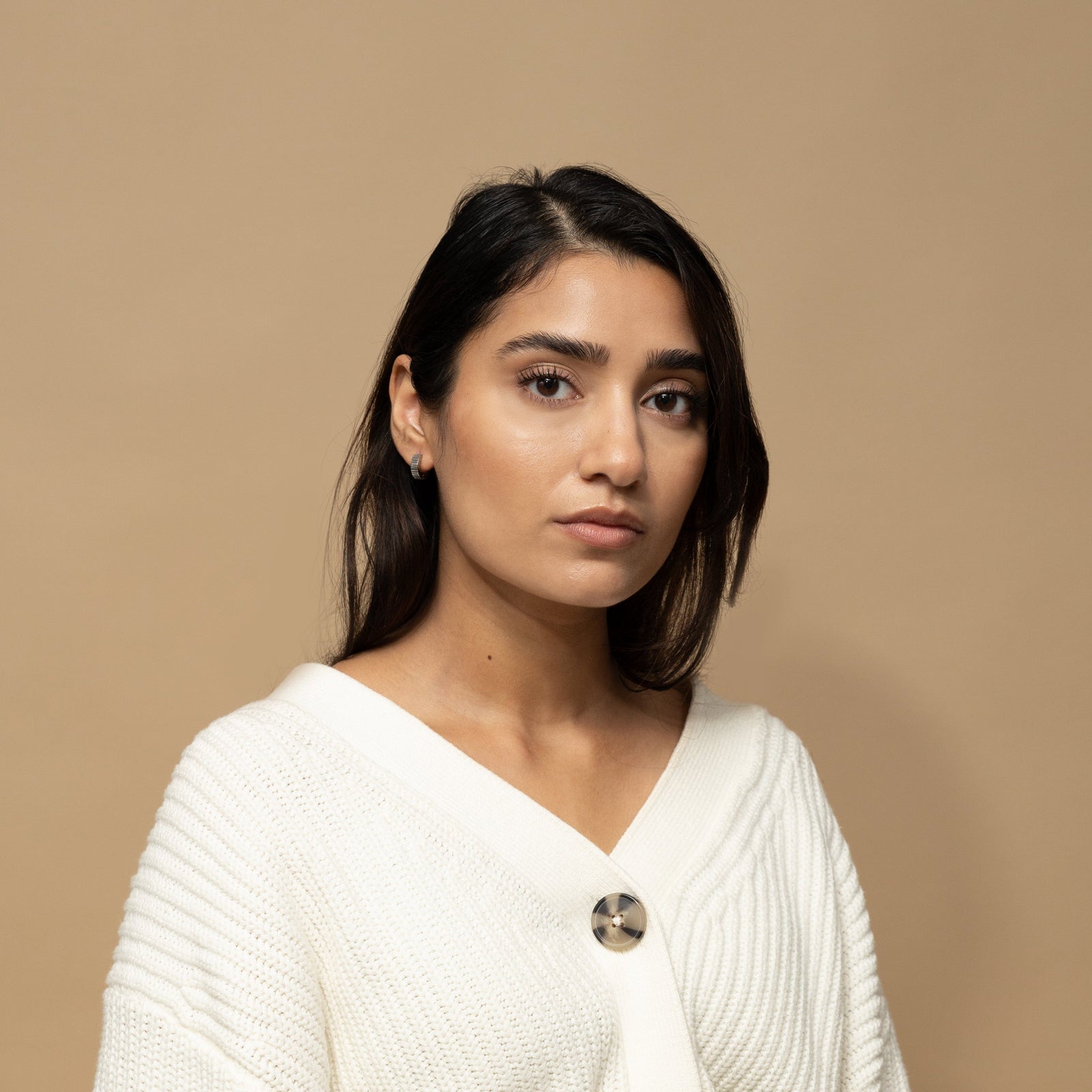 Photo of the model looking at the camera. The model is wearing the silver Ridged Hoop earring on their right ear.