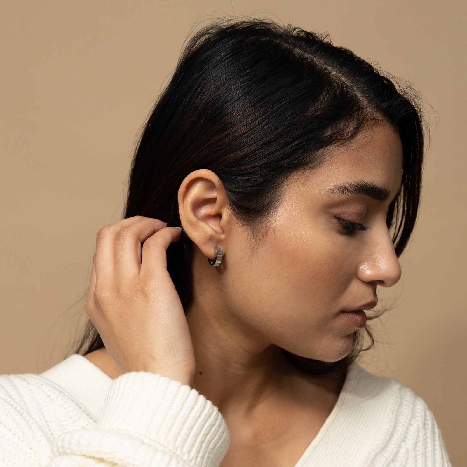Photo of the model's right side profile, the model is wearing the silver Ridged Hoops on their right ear.