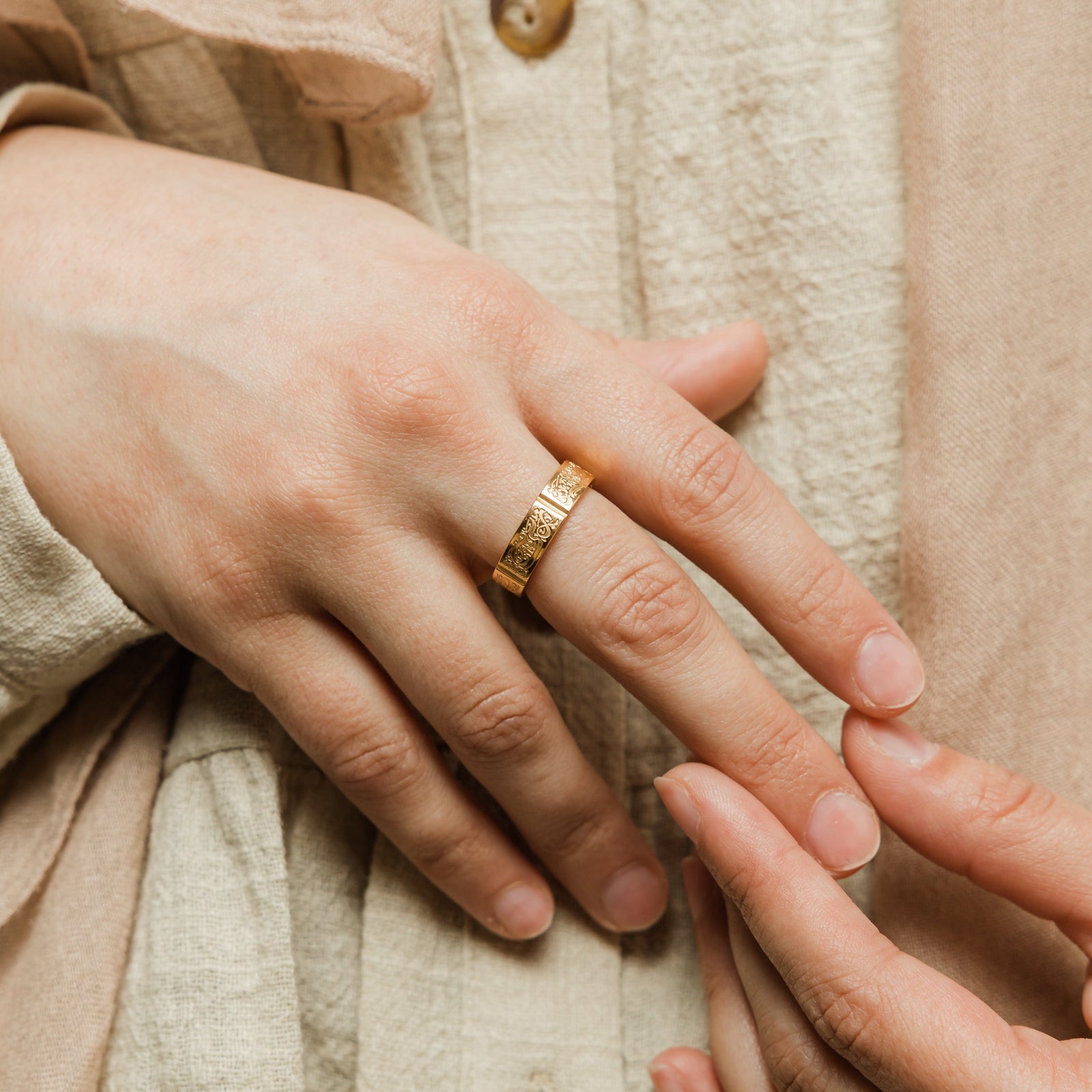 Person wearing the gold Five Pillars Ring on the middle finger, styled with a beige textured outfit.