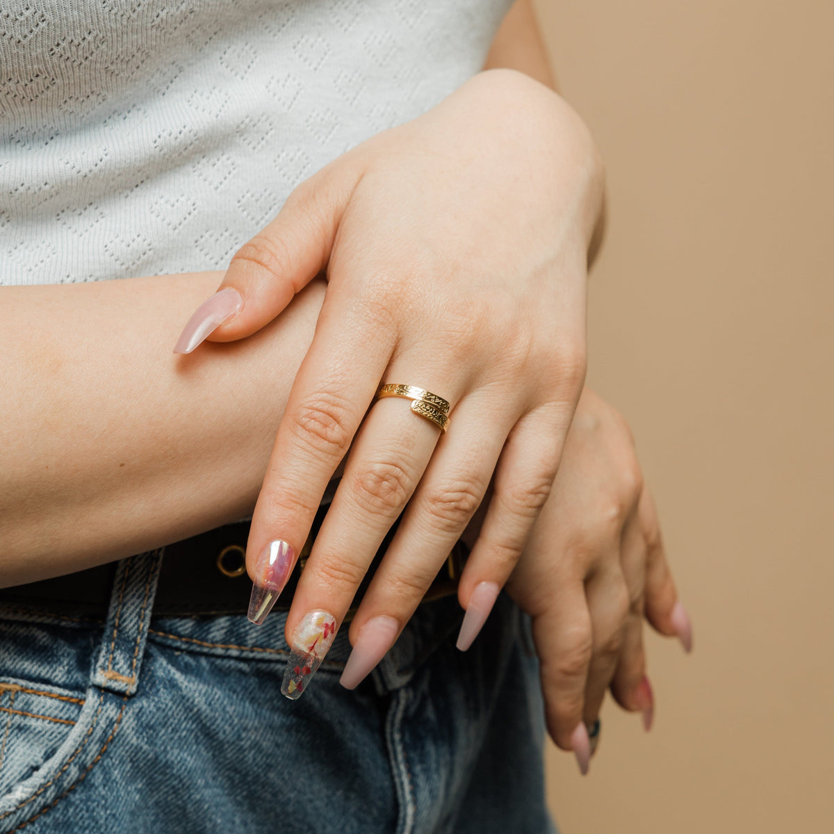 Gold thikr wrap ring with engraved Arabic calligraphy styled on a woman’s hand