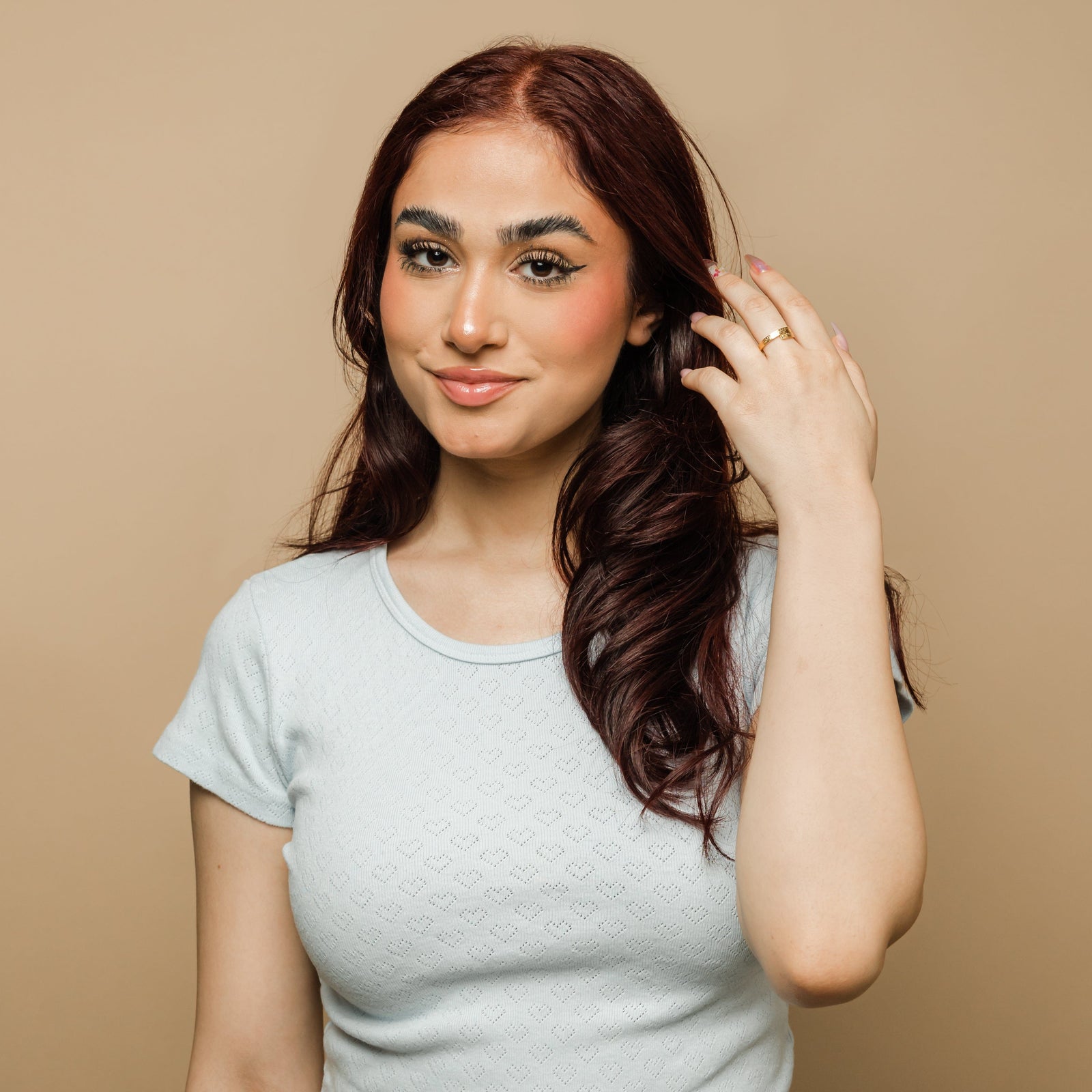 Woman wearing the gold thikr wrap ring with Arabic calligraphy, paired with a light blue textured top.