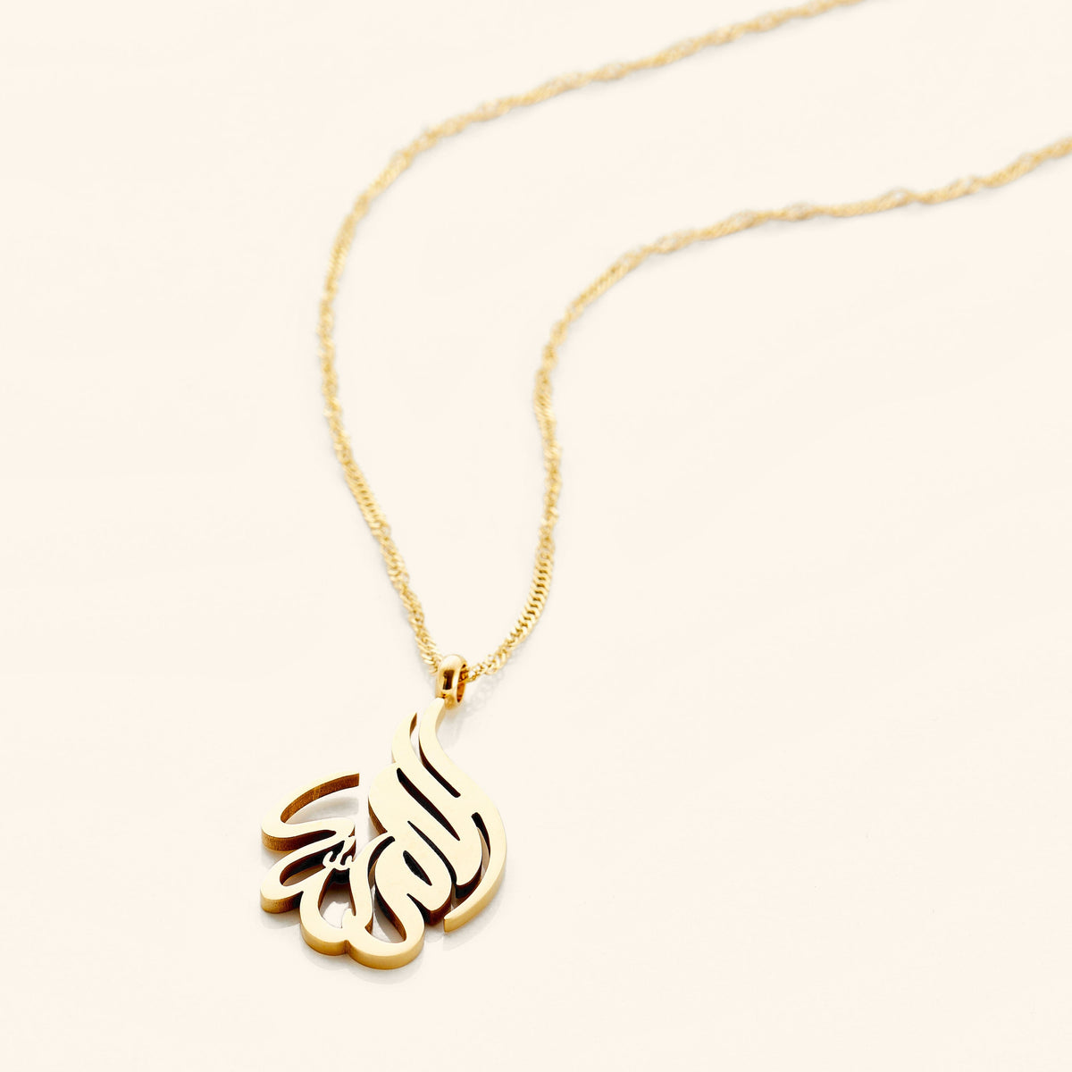 Photo of an 18k gold plated necklace that features calligraphy in Arabic.