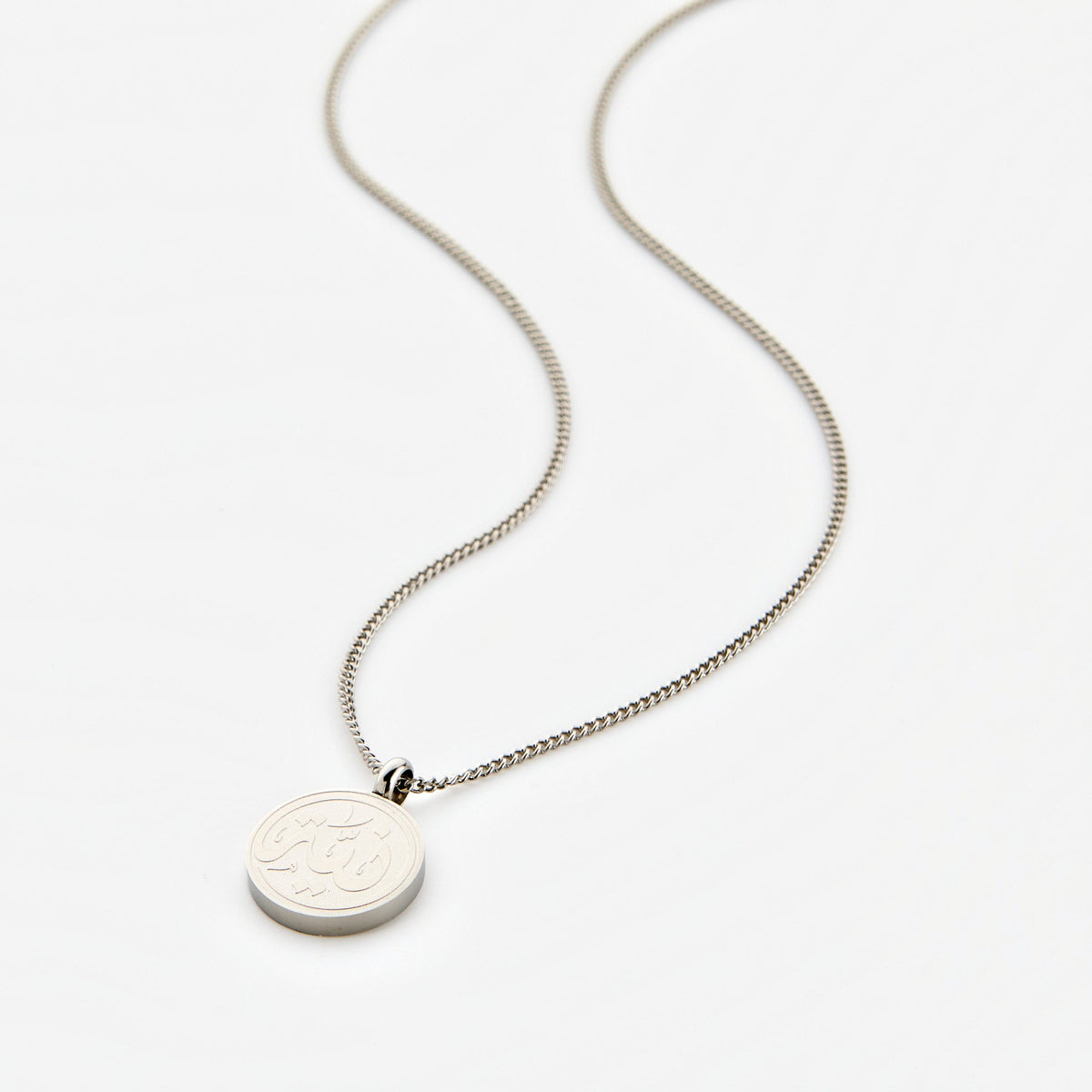 Silver necklace with a circular pendant engraved with 'Niyyah' calligraphy, displayed on a white background.
