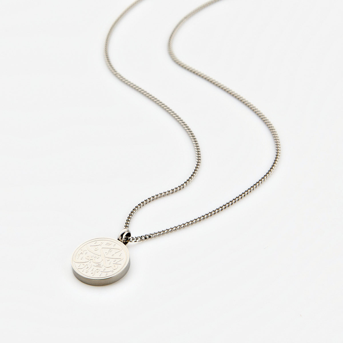 Silver necklace with a circular pendant engraved with 'Maktub' calligraphy, displayed on a white background.