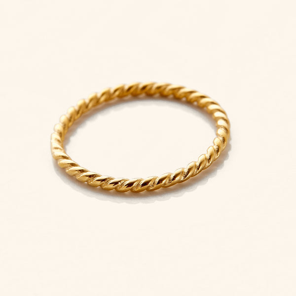 Gold twist ring featuring a delicate rope-like design with a polished finish, displayed flat on a white surface.