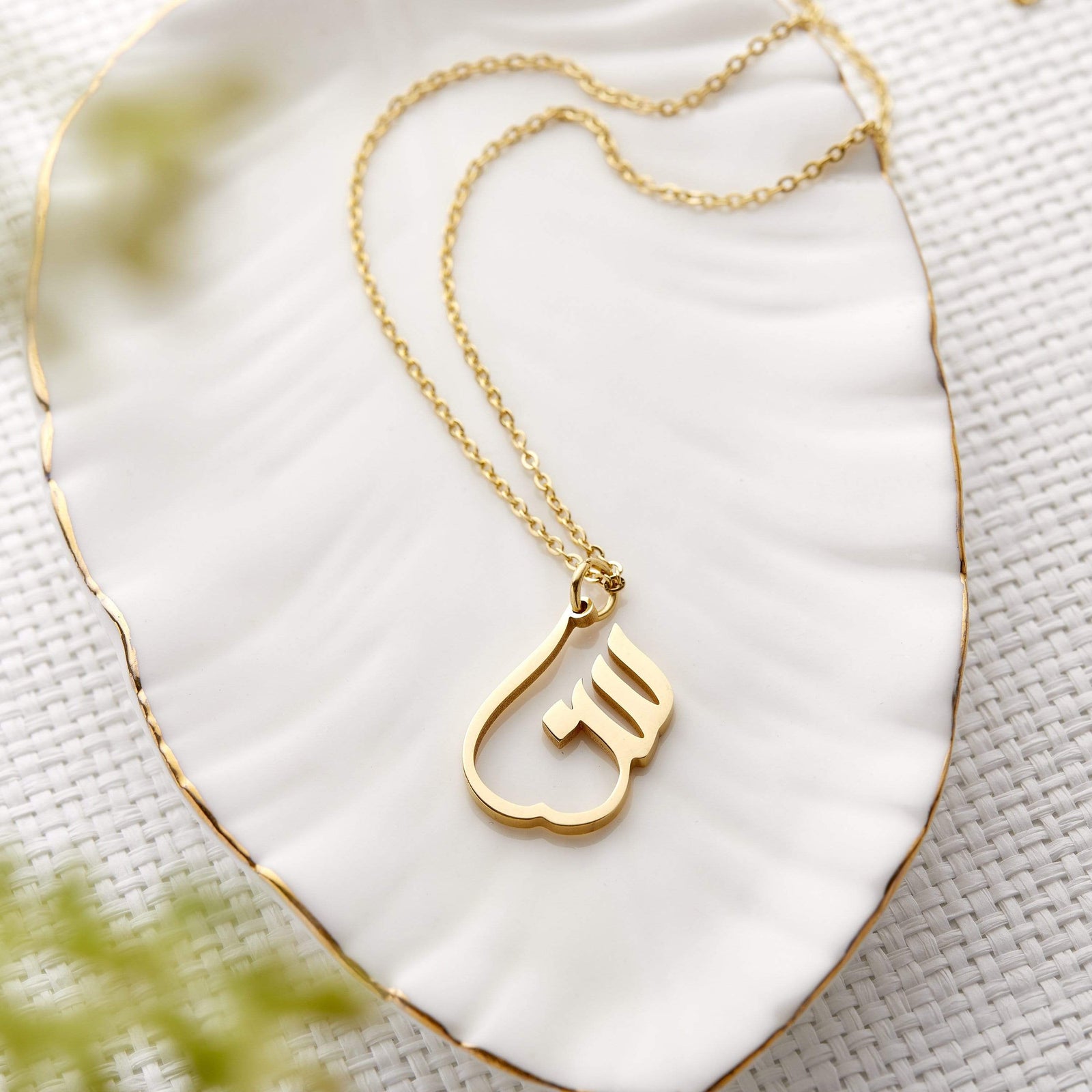 Close up of the gold Ready Calligraphy Name Necklace against a light background.
