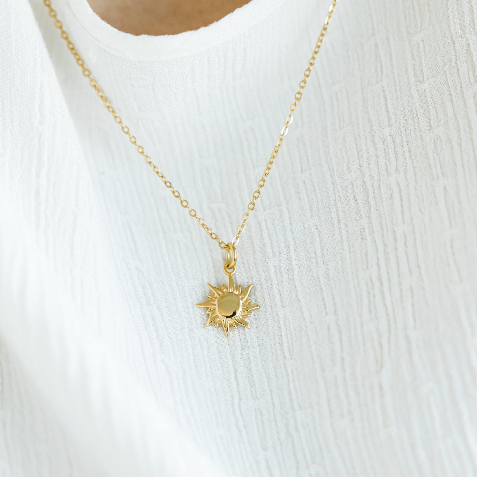 The gold Arizona Sunrise Necklace against the white fabric of the model's clothing.