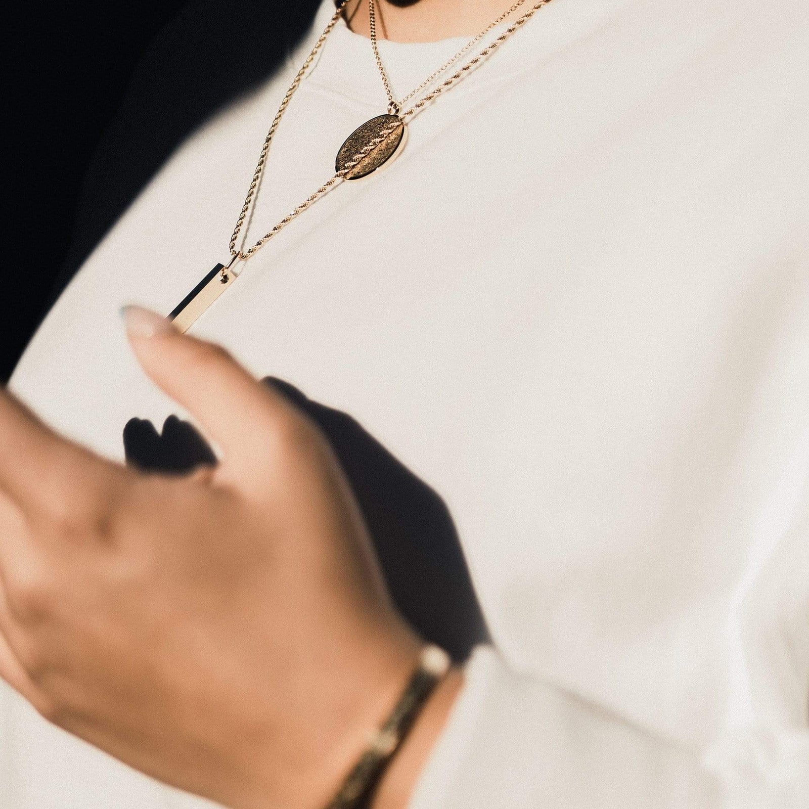 Photo of the model wearing the gold Ayatul Kursi Necklace, Mini Core Values Bar Necklace, and "With Hardship Comes Ease" V2 Cuff.o