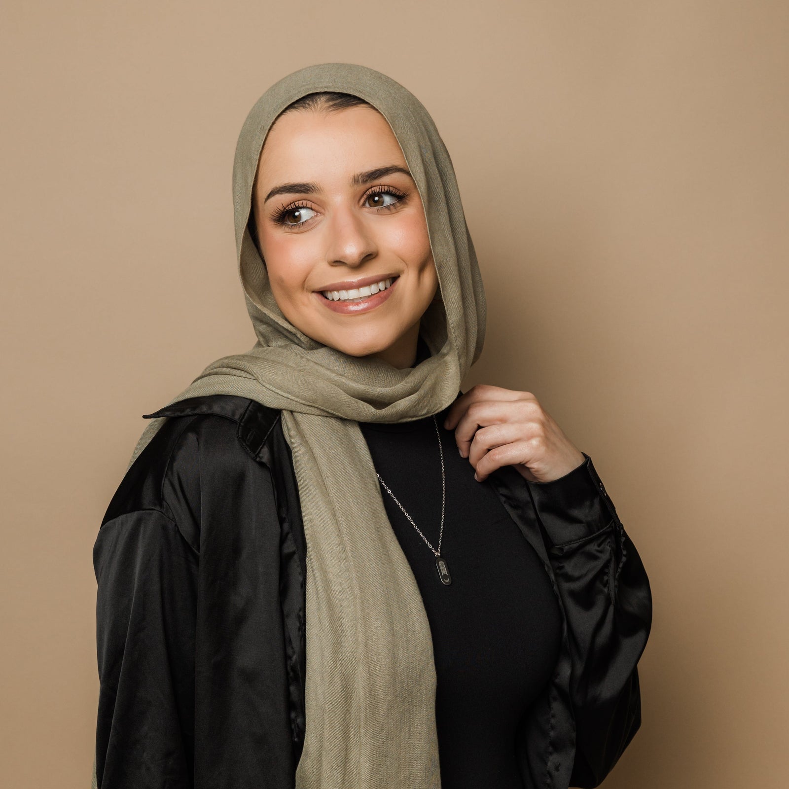 Photo of the model looking away from the camera and smiling. The model is wearing the silver Alhamdulillah Moon Necklace.