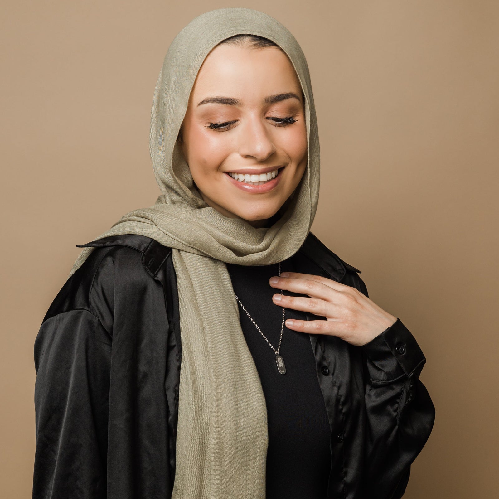 Photo of the model smiling while looking down. The model is wearing the silver Alhamdulillah Moon Necklace | Women.