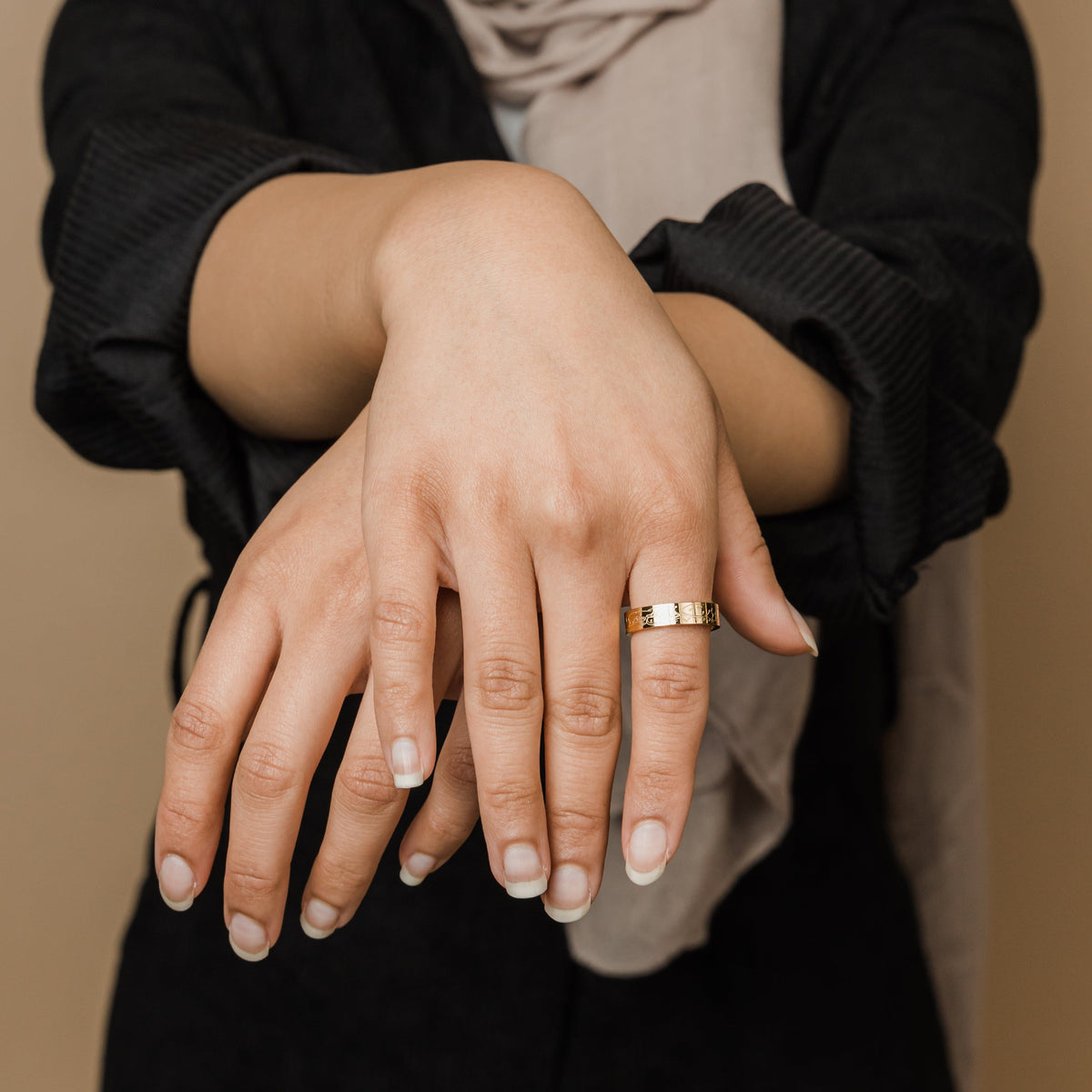 A model wearing the 18K gold-plated "Allah Does Not Burden" ring on her finger. The ring's engraved Arabic inscription is visible.