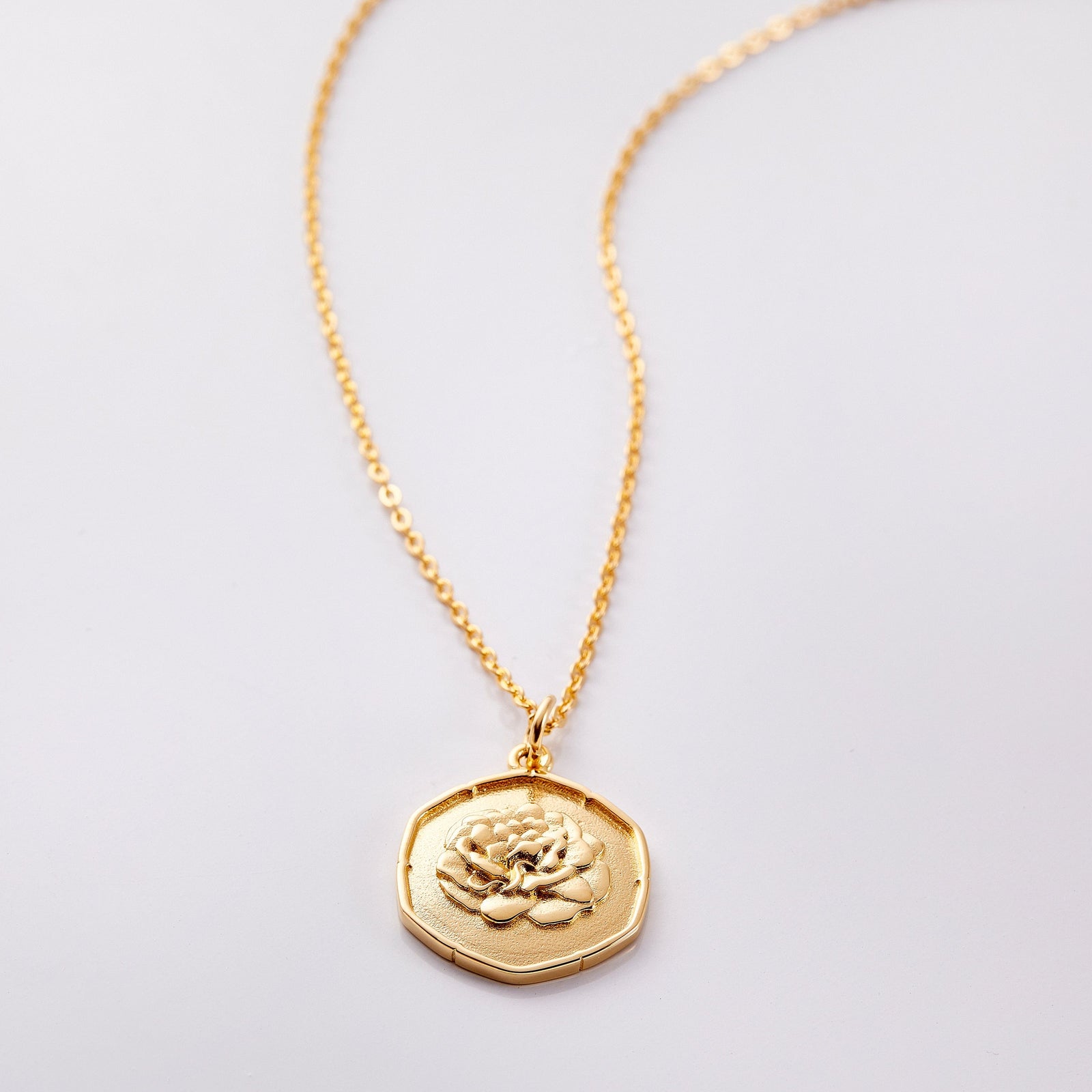 Photo of an 18k golf plated necklace with a pendant that is molded with an imperfect finish, the January Birth Flower is a carnation to represent pride and gratitude