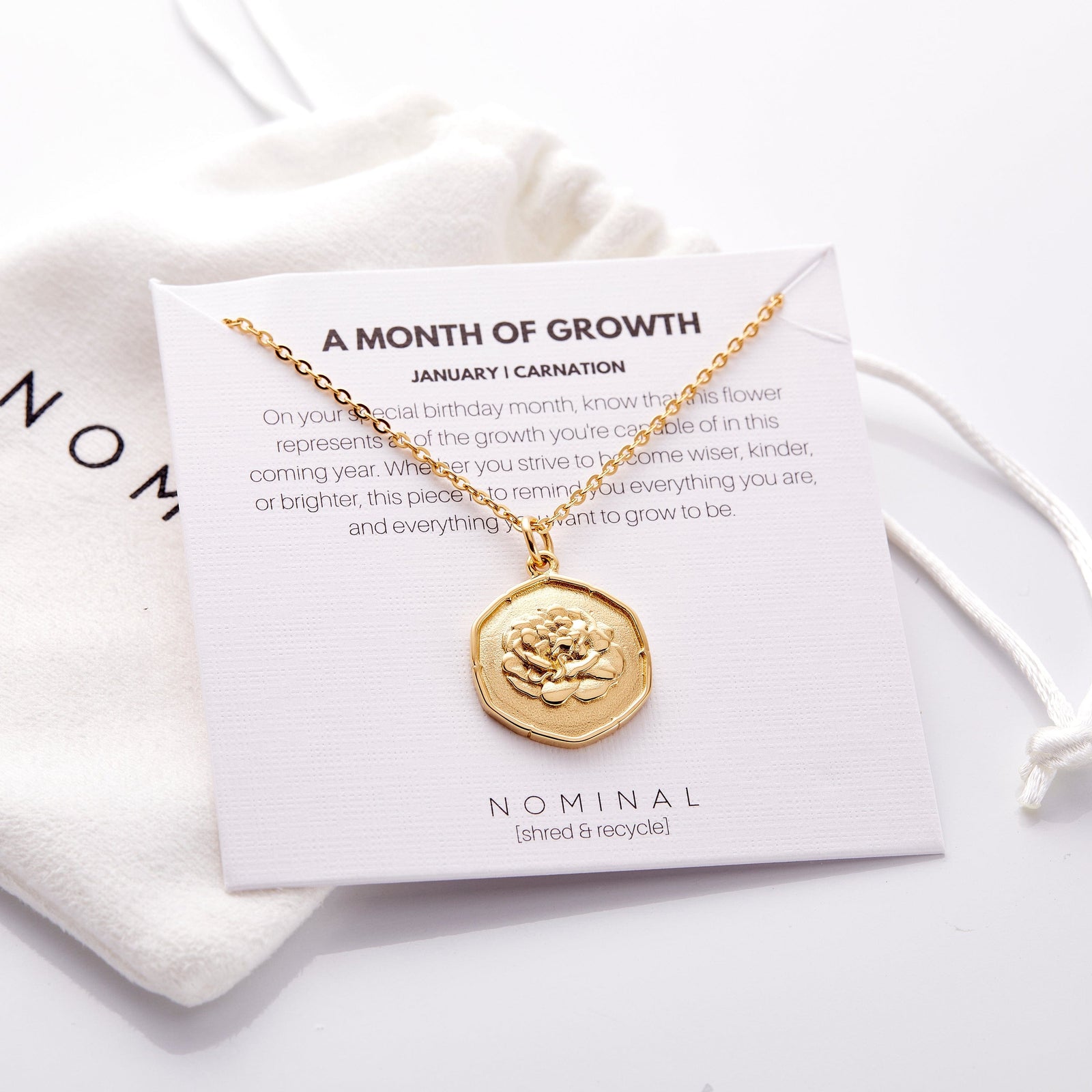 The gold January | Birth Flower Pendant displayed on its packaging that features the description of the jewelry.