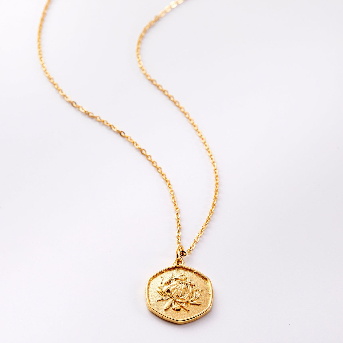 Photo of an 18k golf plated necklace with a pendant that is molded with an imperfect finish, the November Birth Flower is a chrysanthemum to represent joy and love.