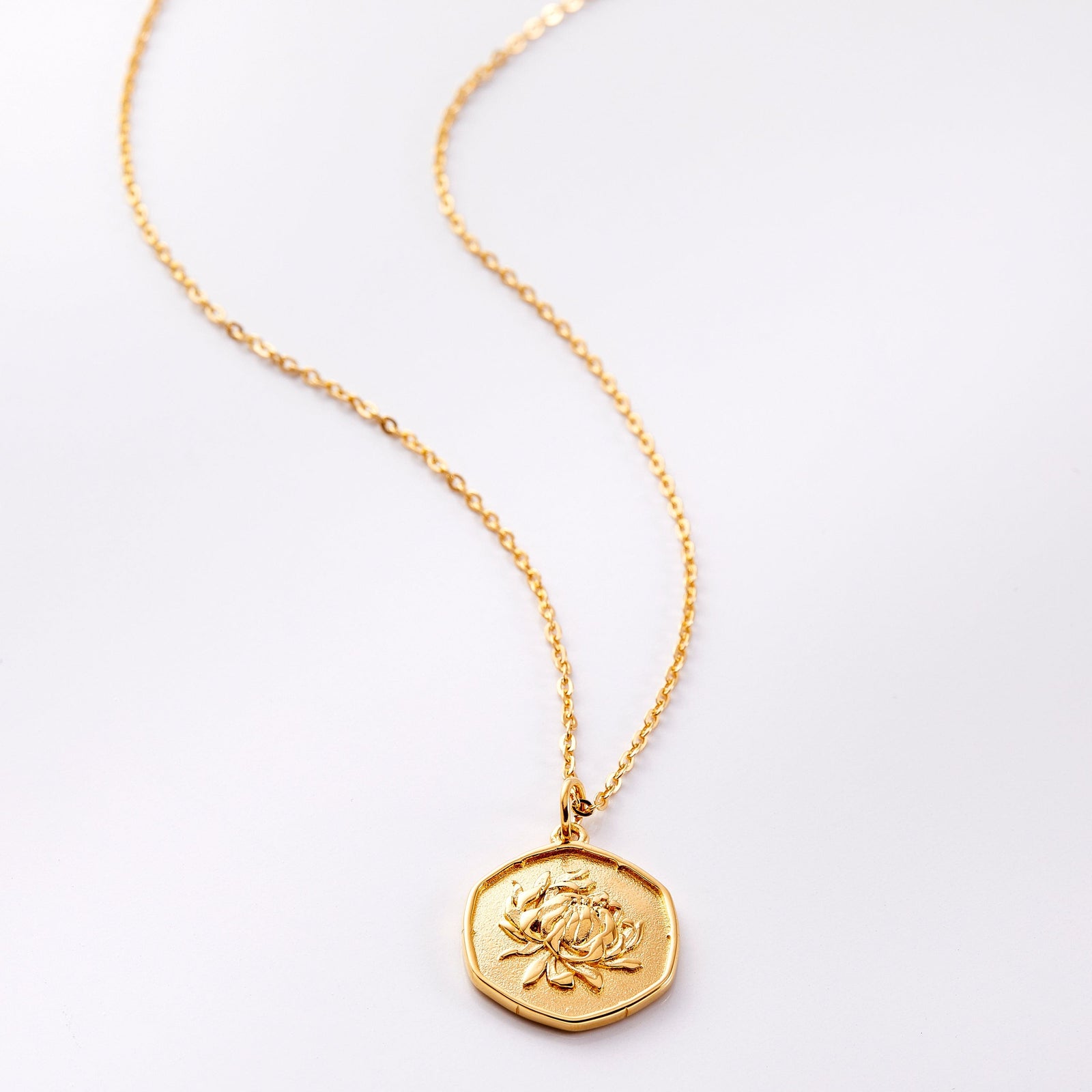 Photo of an 18k golf plated necklace with a pendant that is molded with an imperfect finish, the November Birth Flower is a chrysanthemum to represent joy and love.