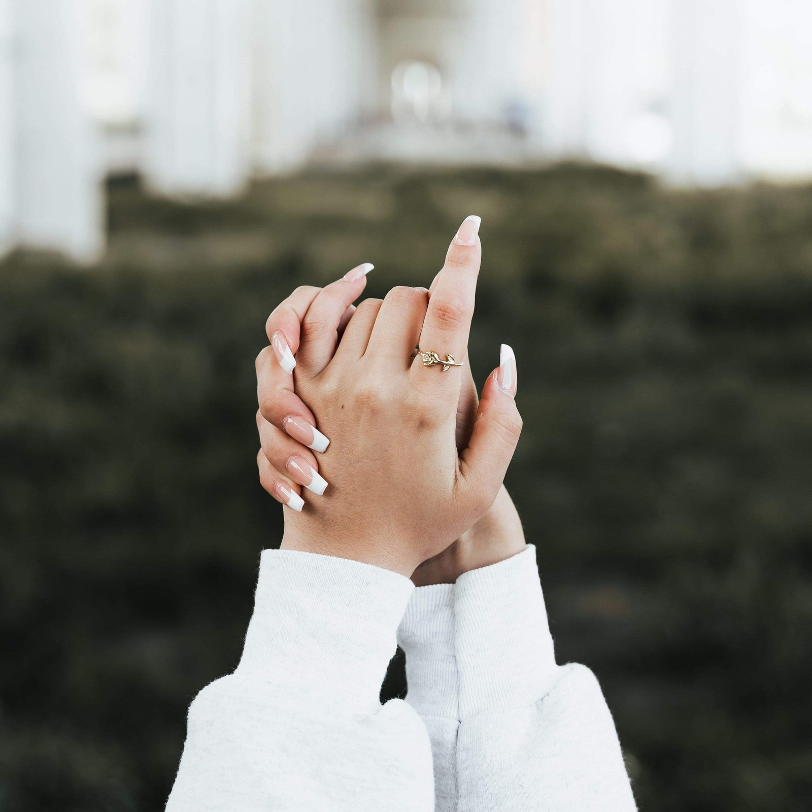Close-up of hands with wearing a gold rose ring on the index finger.