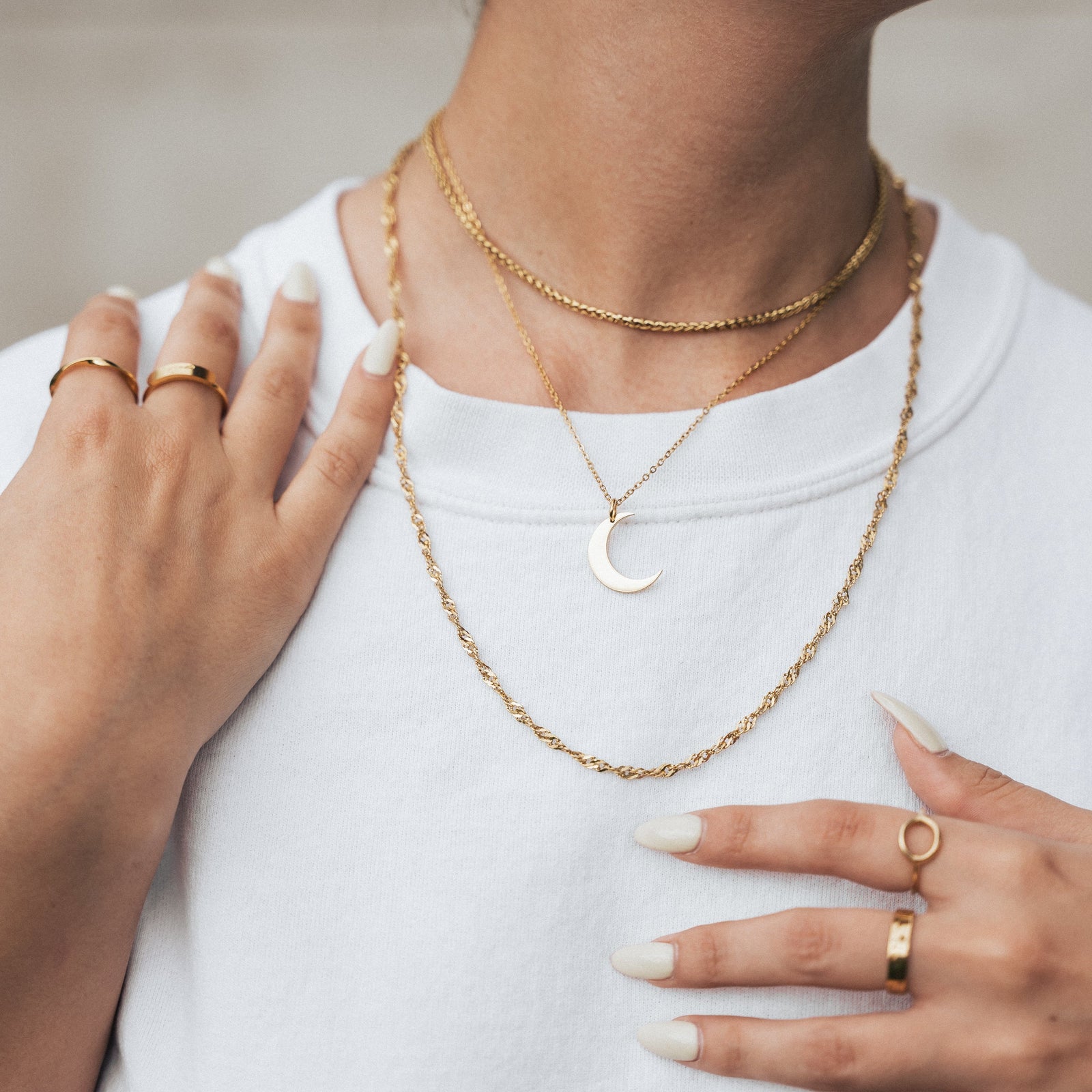 The gold Crescent Moon Necklace as worn and layered with other set of necklaces by the model.