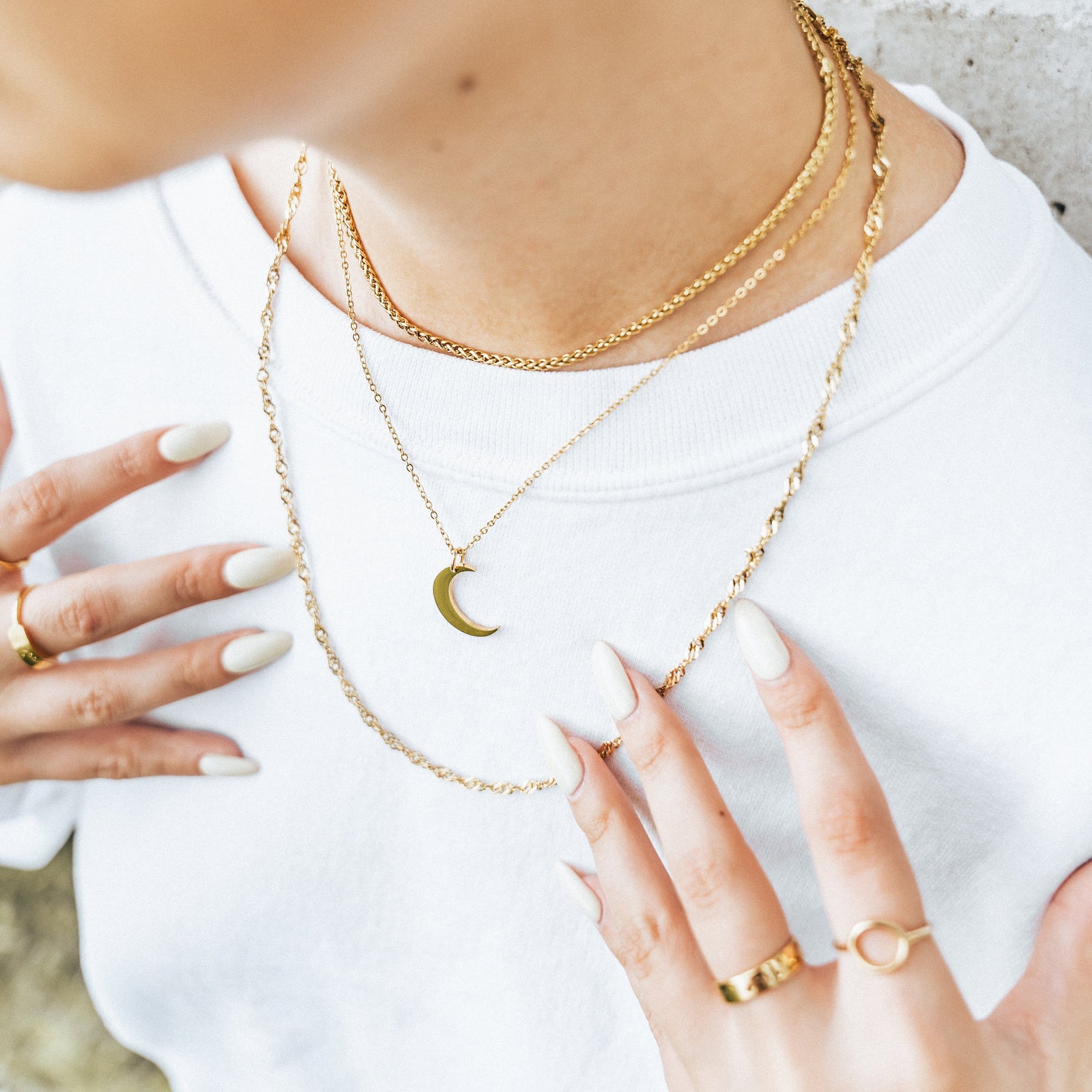 The gold Crescent Moon Necklace as worn and layered with other set of necklaces by the model.