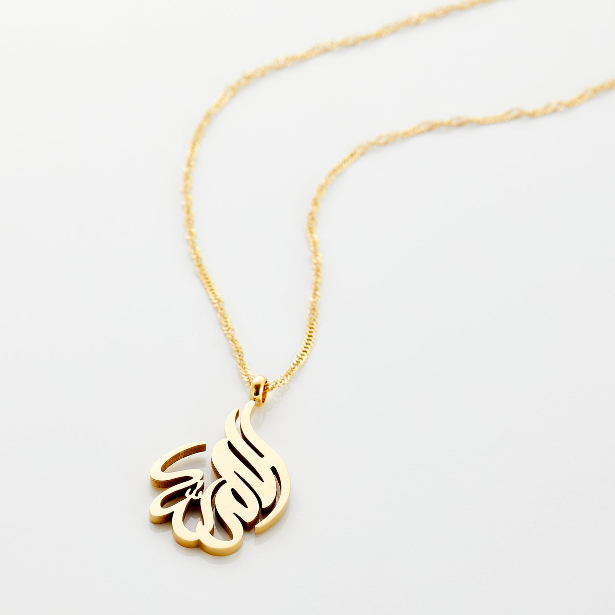 Photo of an 18k gold plated necklace that features calligraphy in Arabic.