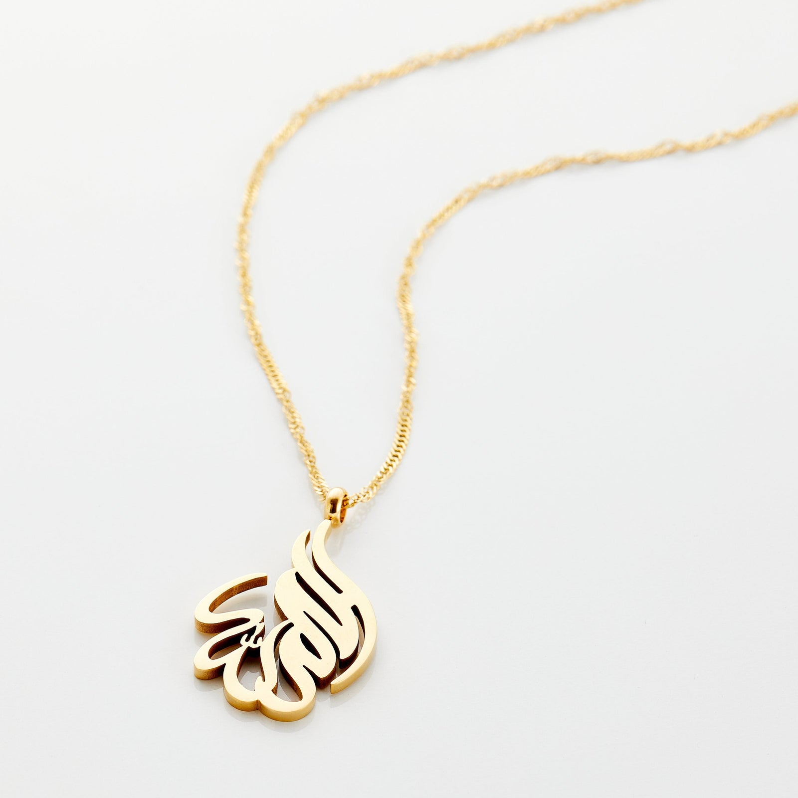 Photo of an 18k gold plated necklace that features calligraphy in Arabic.