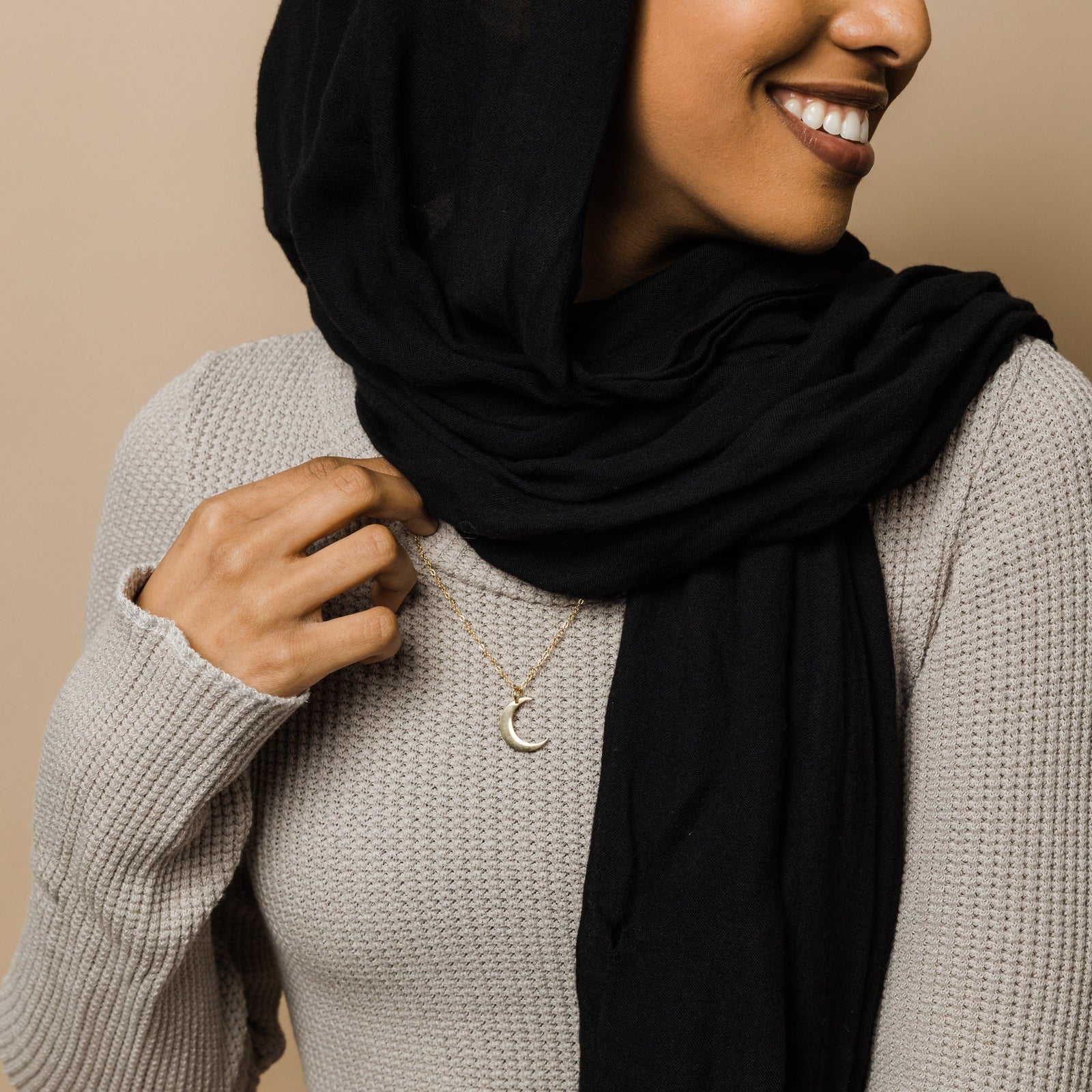 Close up of the gold Crescent Moon Necklace as worn by the model. 