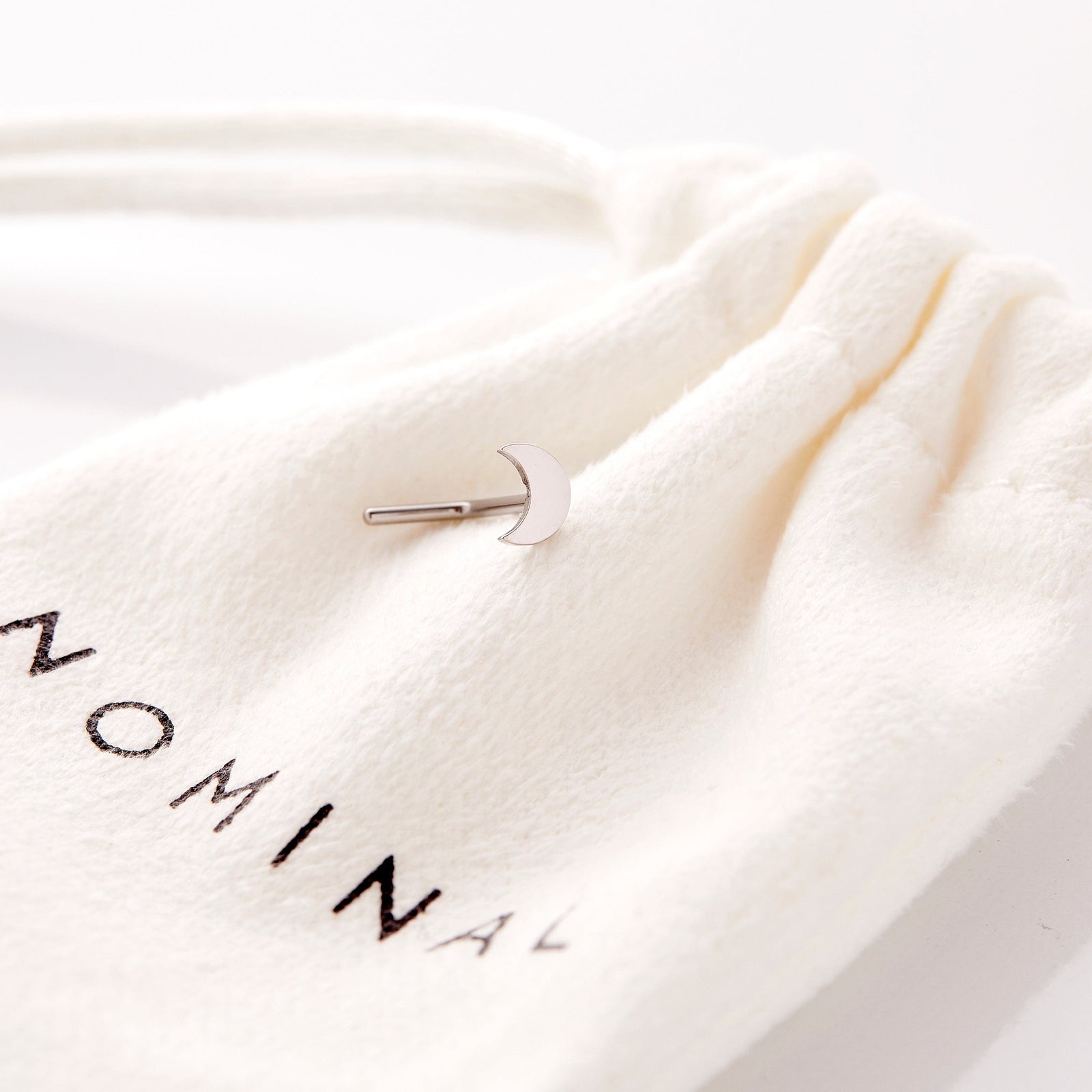 the silver Crescent Stud Nose Ring resting on the Nominal pouch