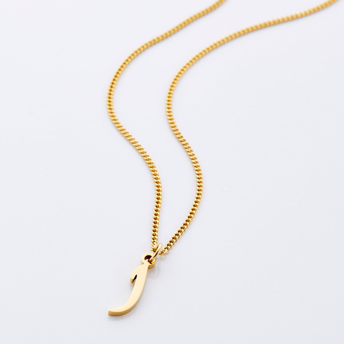 Flat lay of an 18k gold plated necklace that features one hanging letter, brought together by an elegant curb chain.
