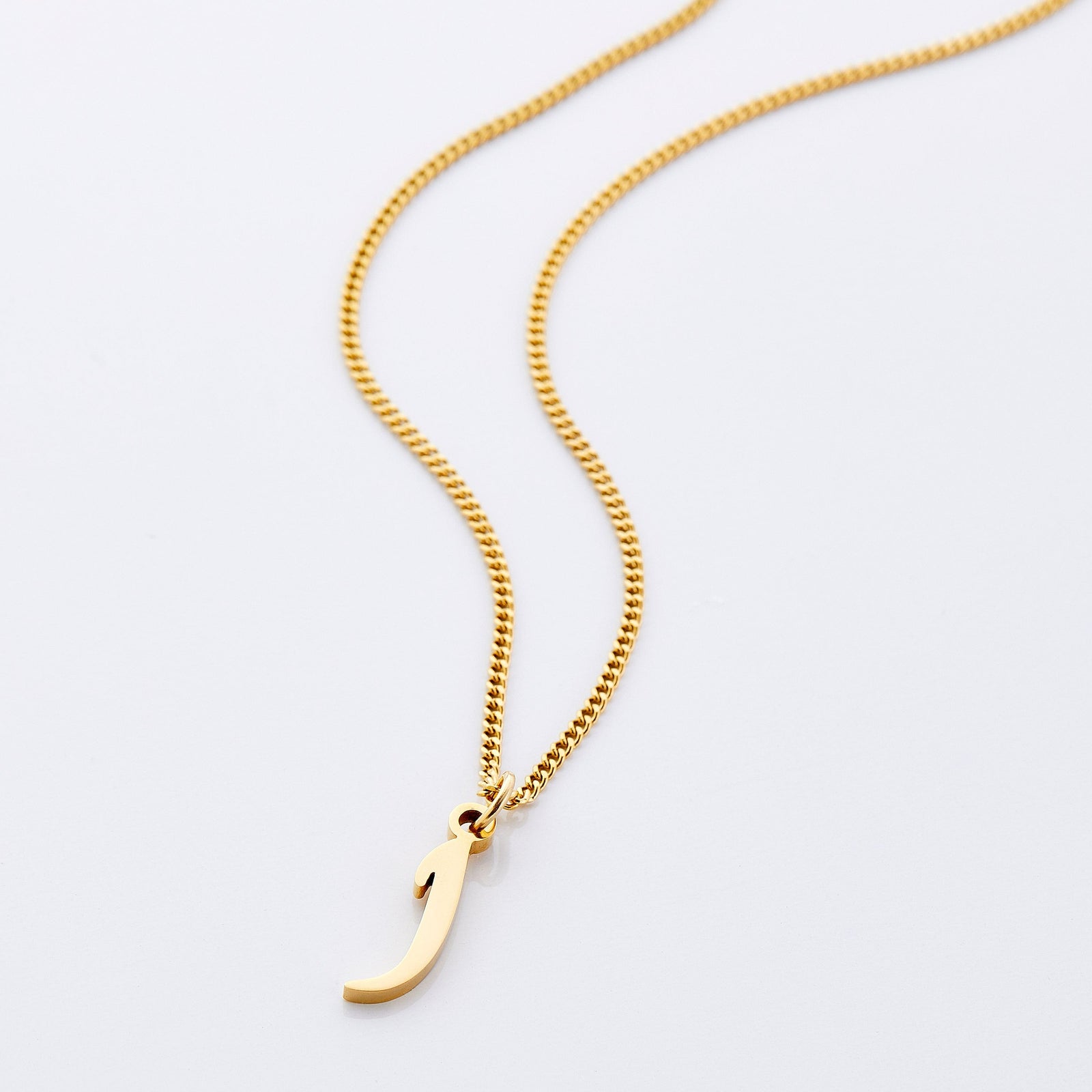 Flat lay of an 18k gold plated necklace that features one hanging letter, brought together by an elegant curb chain.