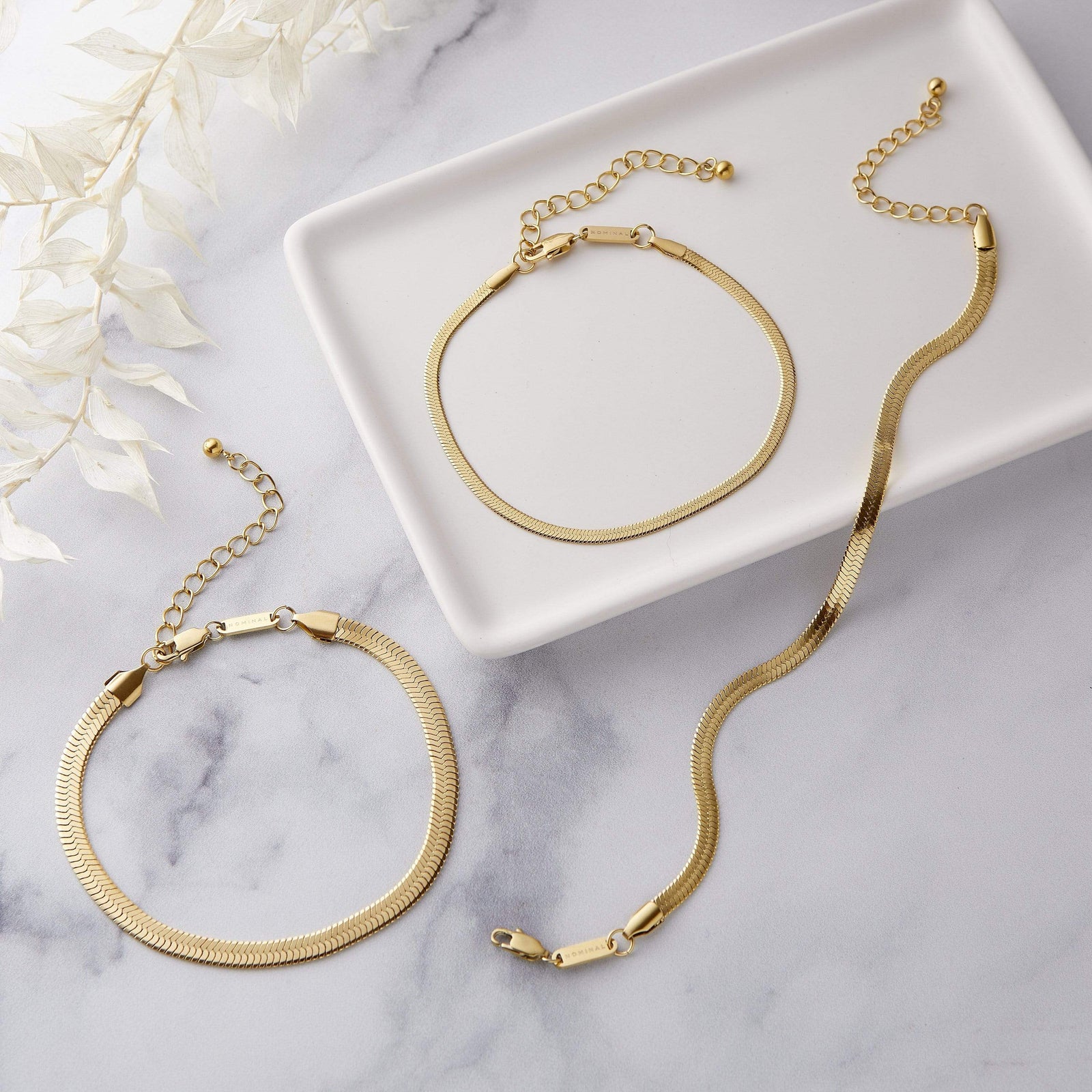 Photo of three 18k gold plated Herringbone Chain anklet in three different sizes.