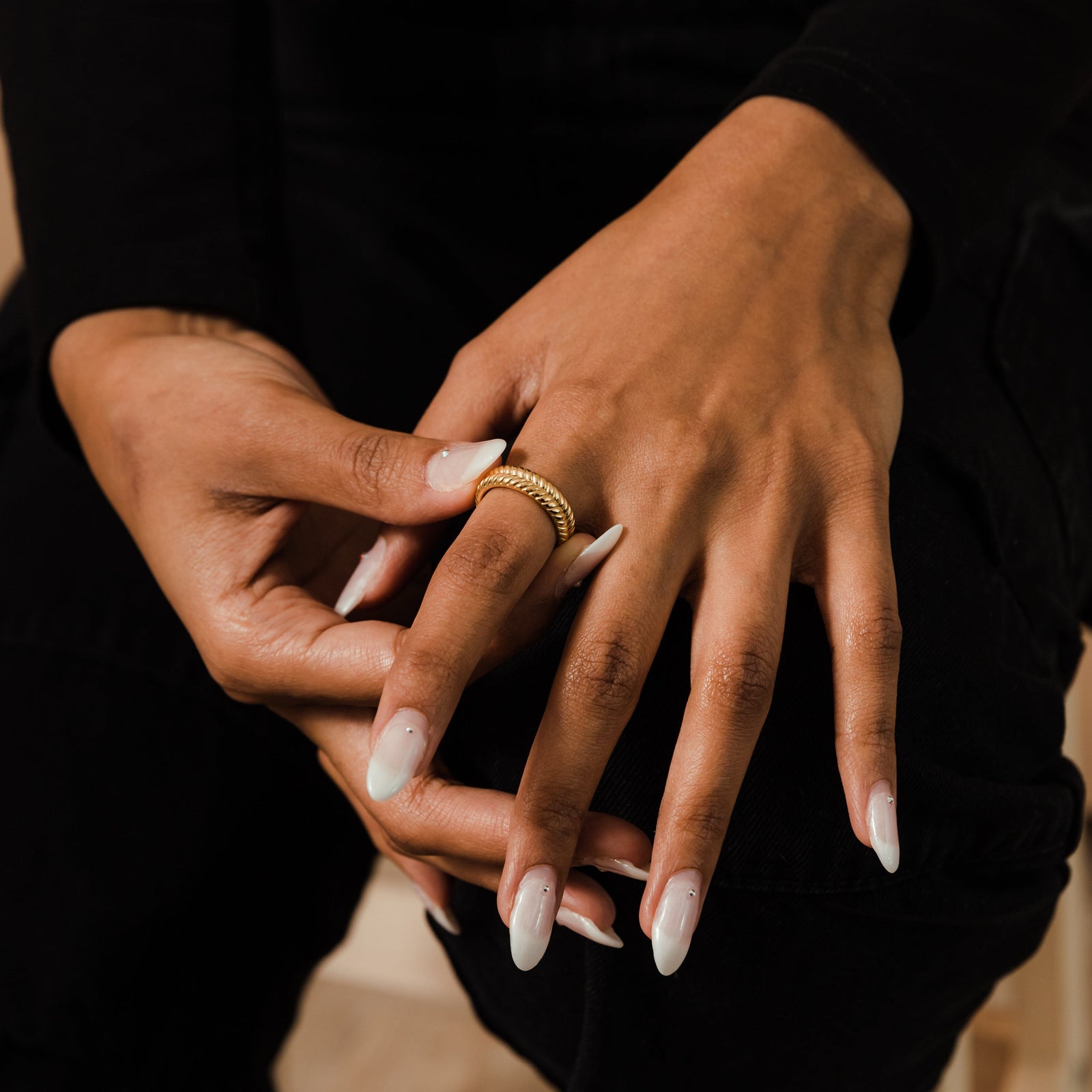 Woman’s hands adjusting the gold herringbone ring on her finger.