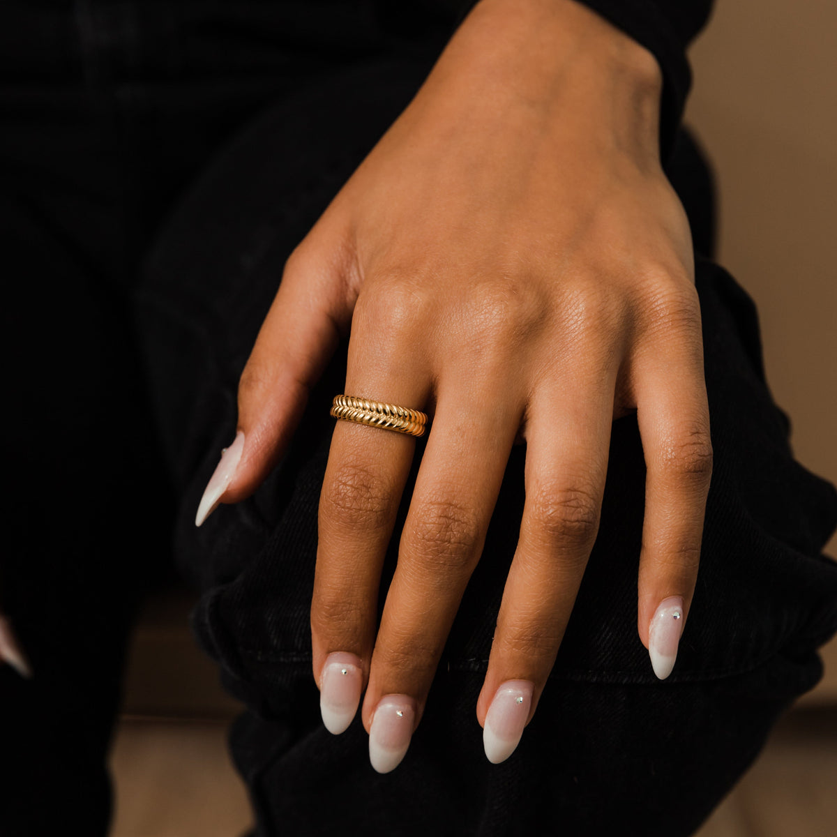 Woman’s hand wearing the gold herringbone ring on the index finger.