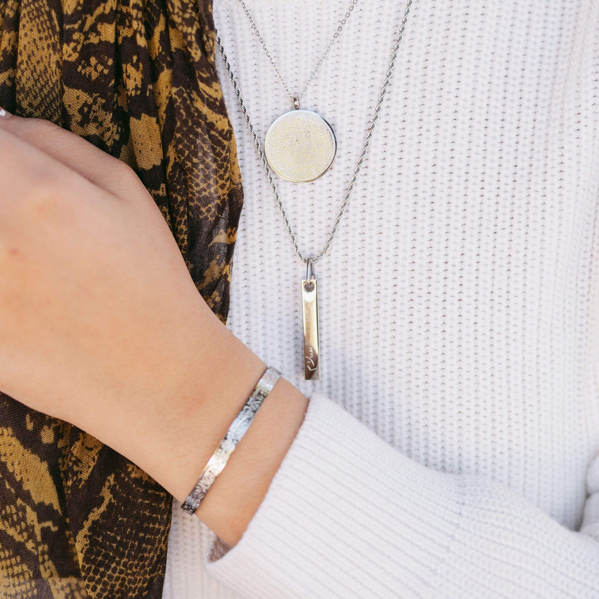 Model wearing the silver Ayatul Kursi Necklace, Mini Core Values Bar Necklace, and "With Hardship Comes Ease" V2 Cuff.