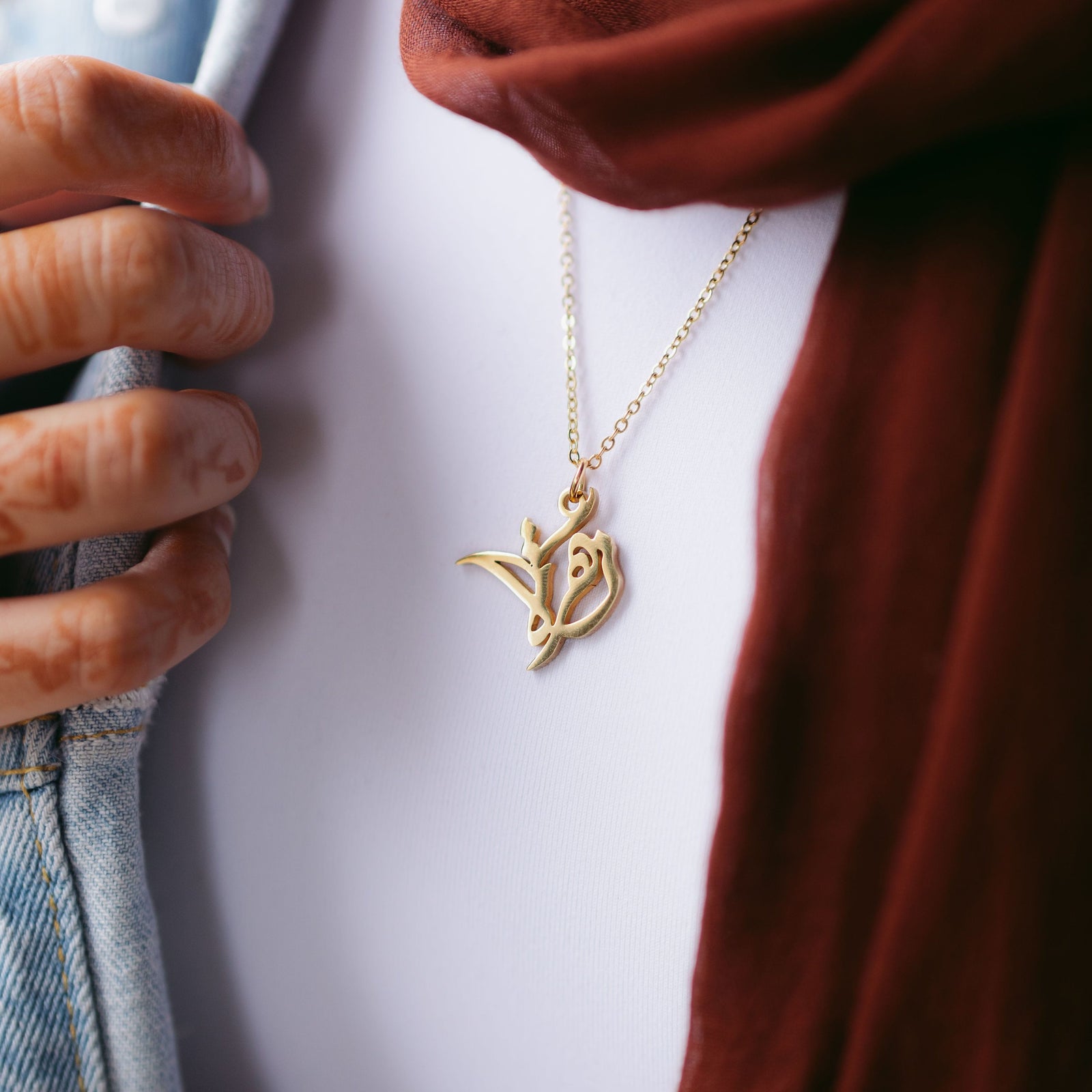 Close up of the gold Ready Calligraphy Name Necklace as worn by the model
