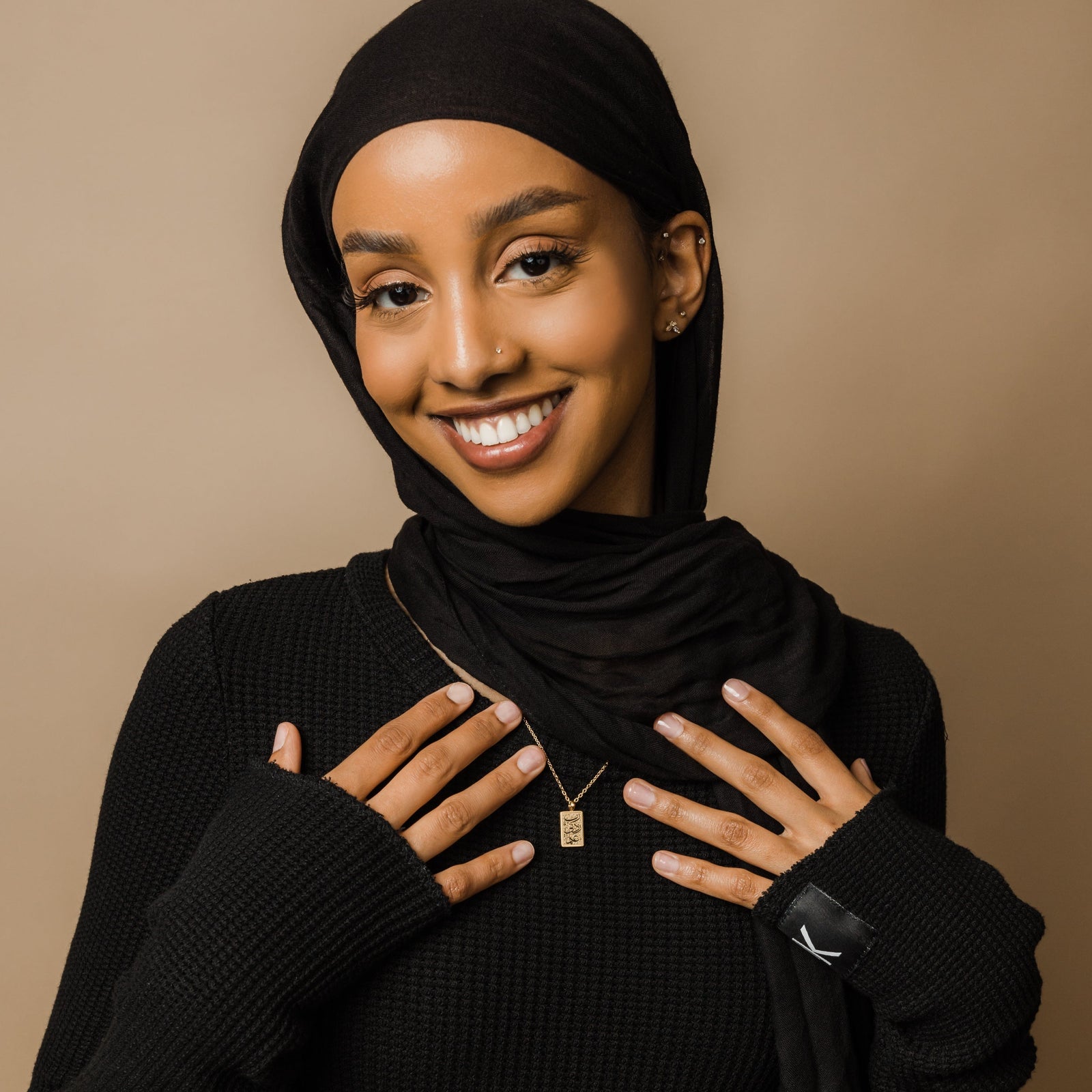 Photo of the model smiling to the camera wearing the gold Knowledge Necklace.