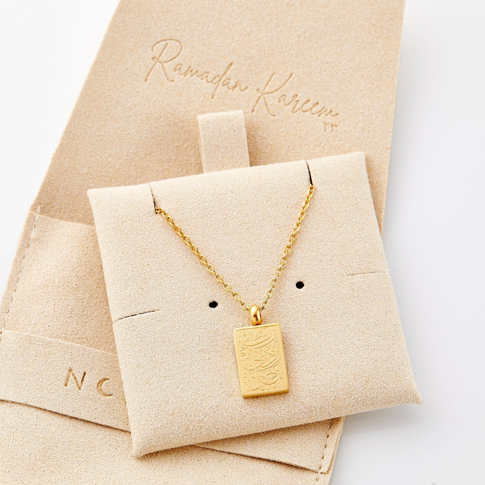 The gold Knowledge Necklace on its packaging.