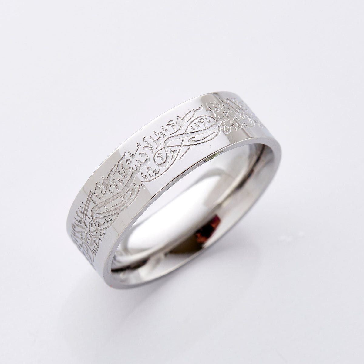 Photo of a silver band ring that is designed with an Arabic Calligraphy that engraving that means "Verily, with hardship comes ease. With hardship comes ease."