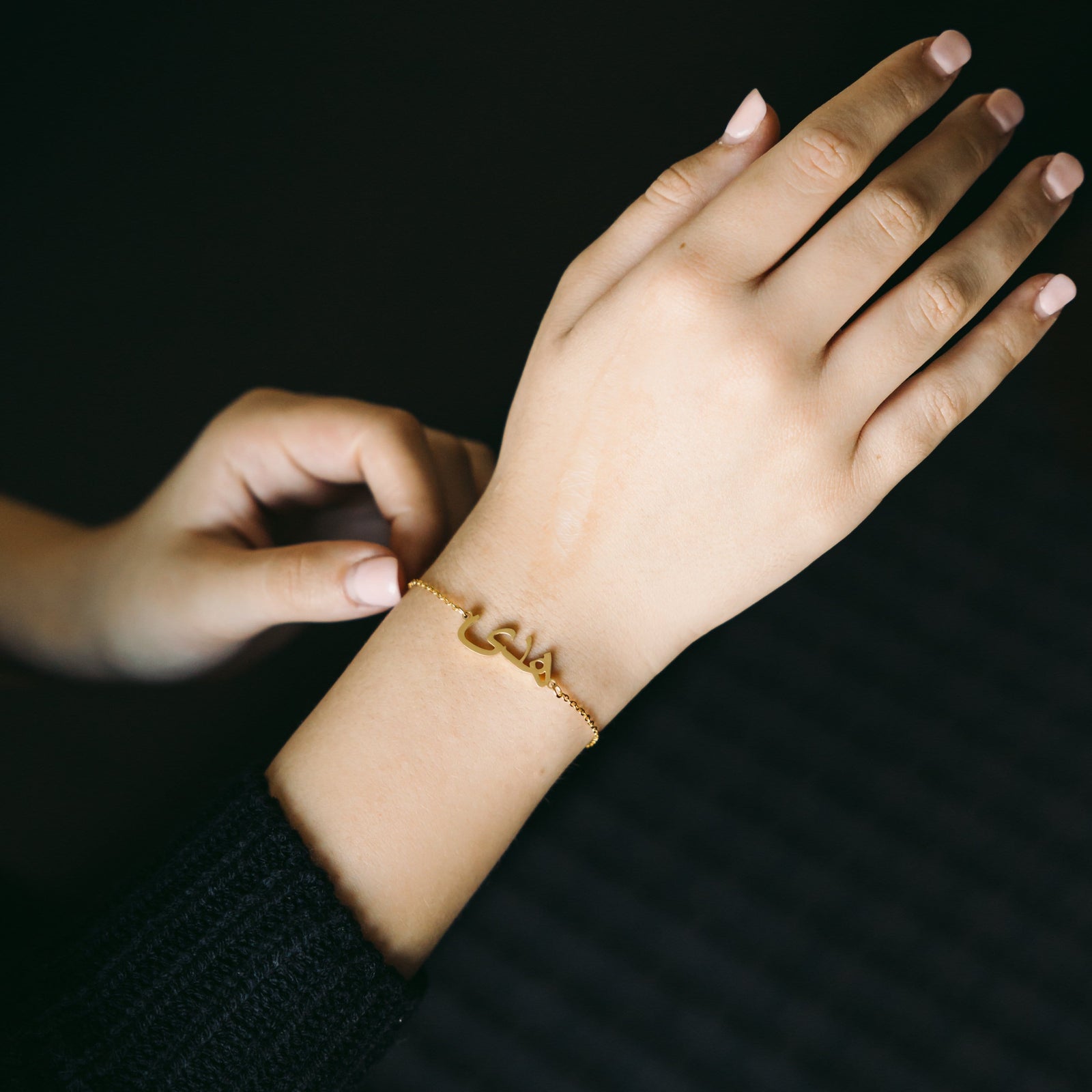 Photo of the model's right hand. The model is wearing the gold Custom Name Bracelet