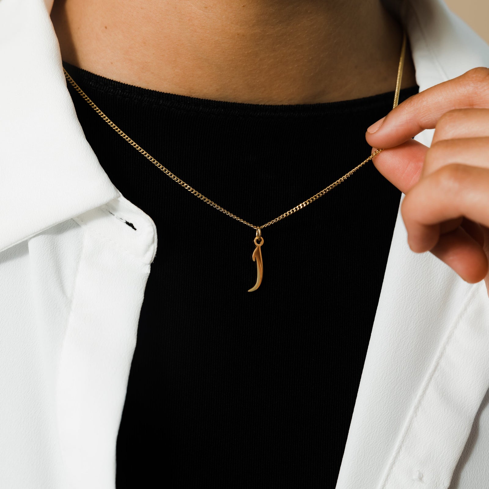 Close up of the Hanging Arabic Letter Necklace as worn by the model.
