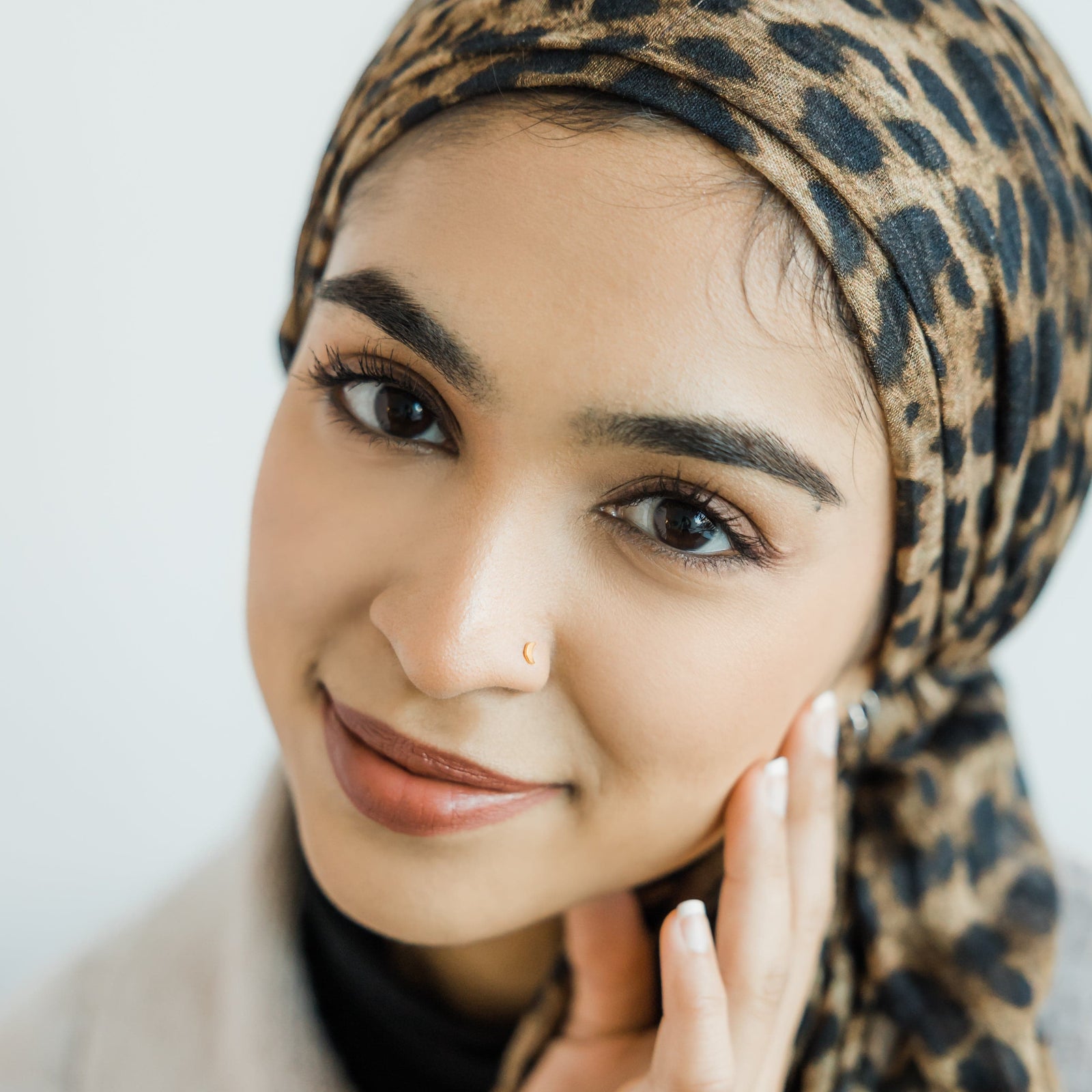 Photo of the model smiling to the camera. The model is wearing the gold Crescent Stud Nose Ring