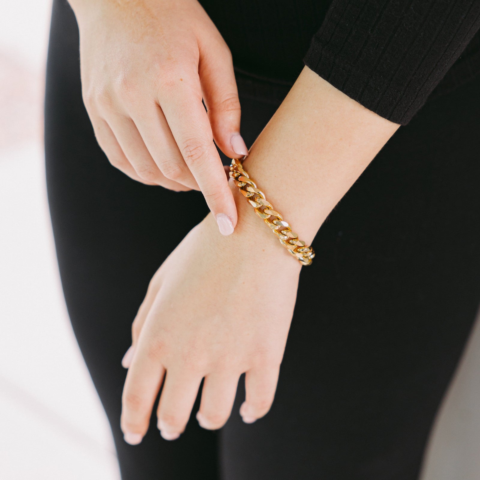 Close up of the model touching the  gold Chunky Cuban Chain Bracelet as worn on their left hand.