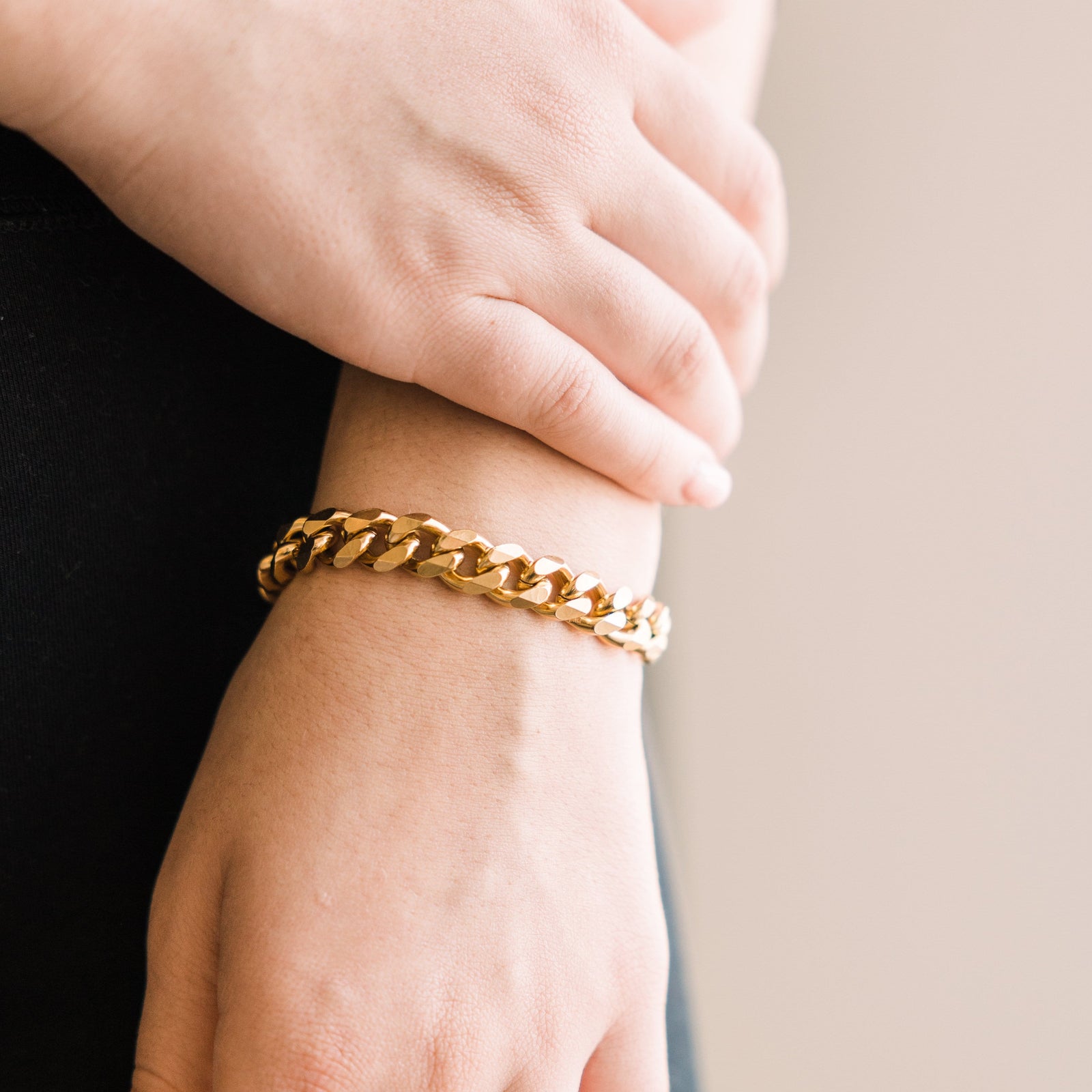 Close up of the gold Chunky Cuban Chain Bracelet as worn by the model on their left hand.